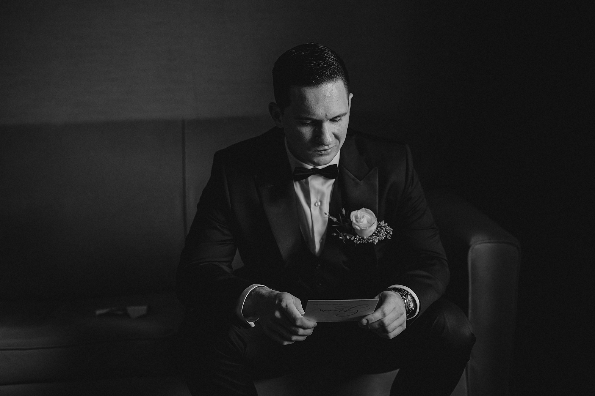 groom sits in chair to read letter 