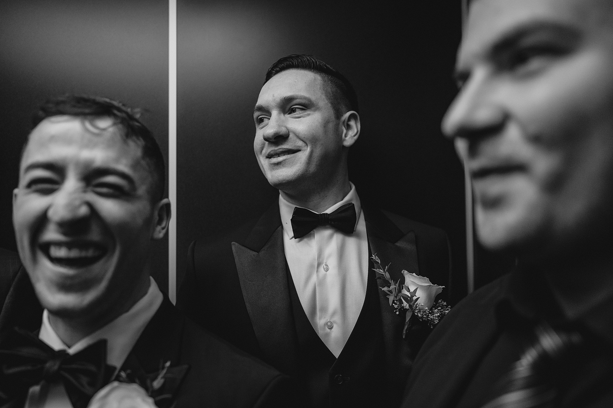 groom smiles looking over shoulder behind groomsmen 