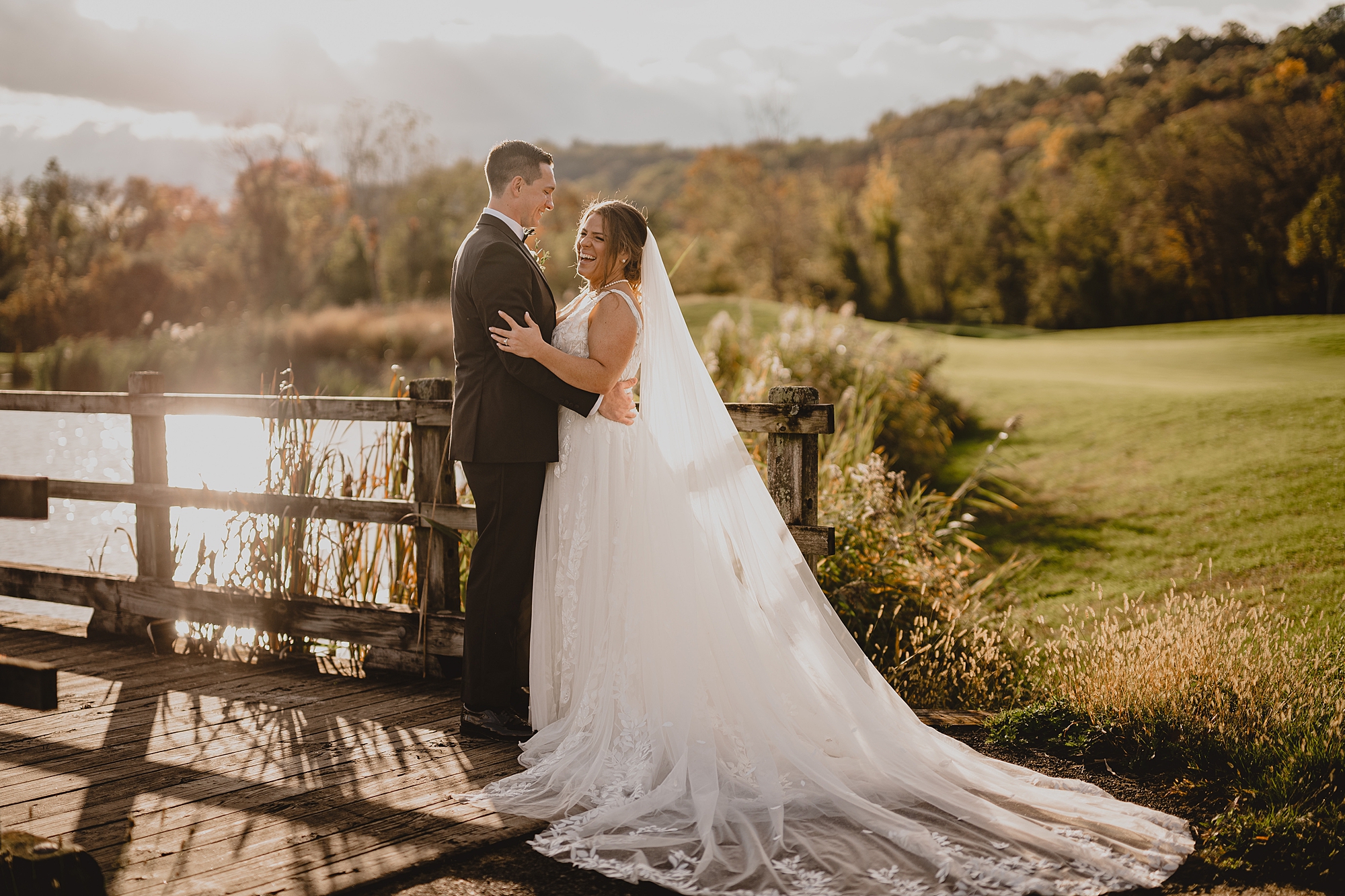 groom looks down at bride smiling at her near pond at Hollow Brook Golf Club