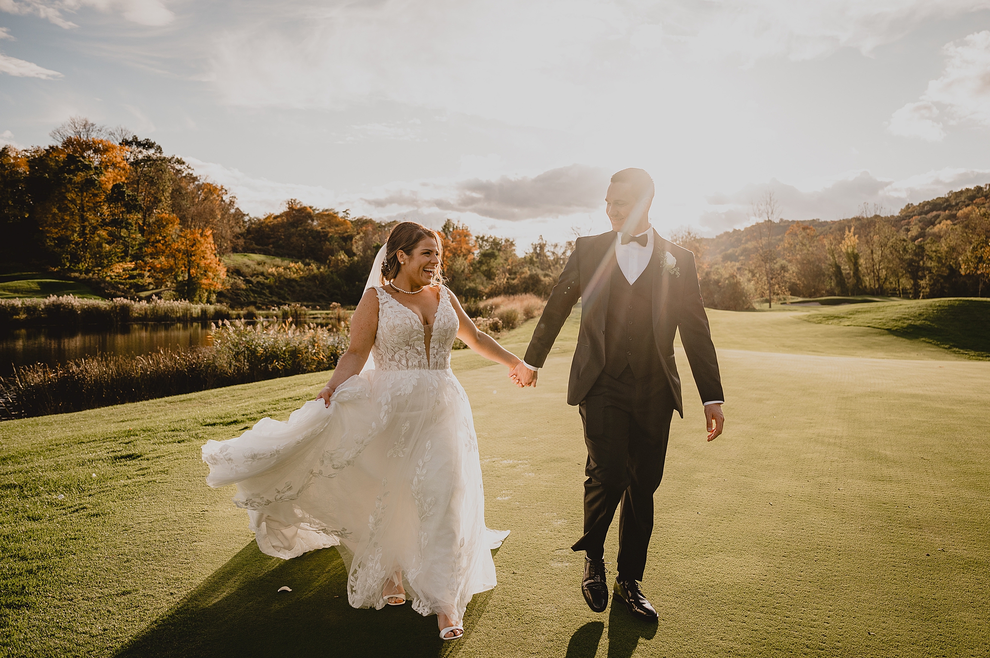 groom holds bride's hand walking on putting green