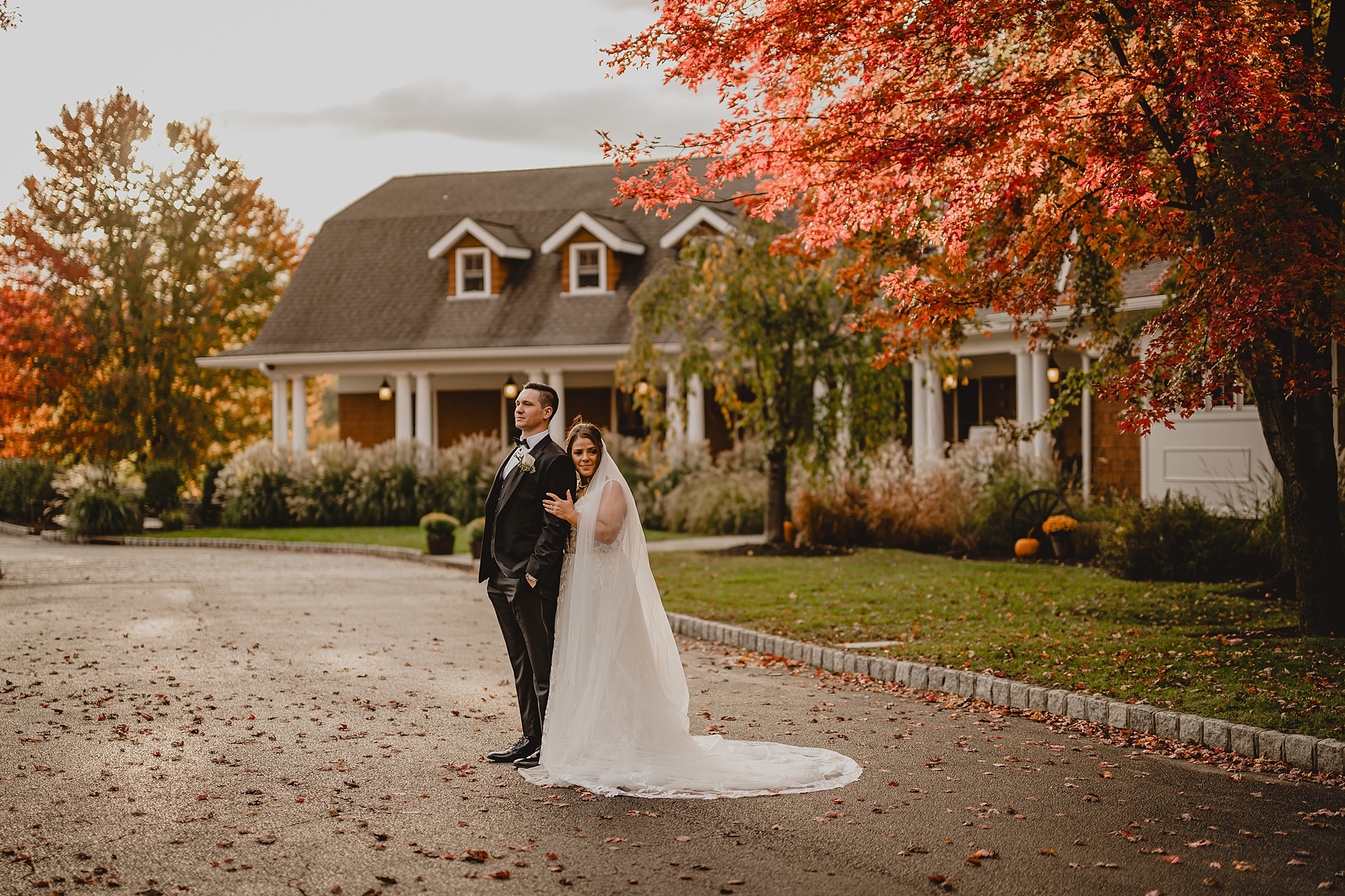 bride stands behind groom hugging his arm in front of Hollow Brook Golf Club