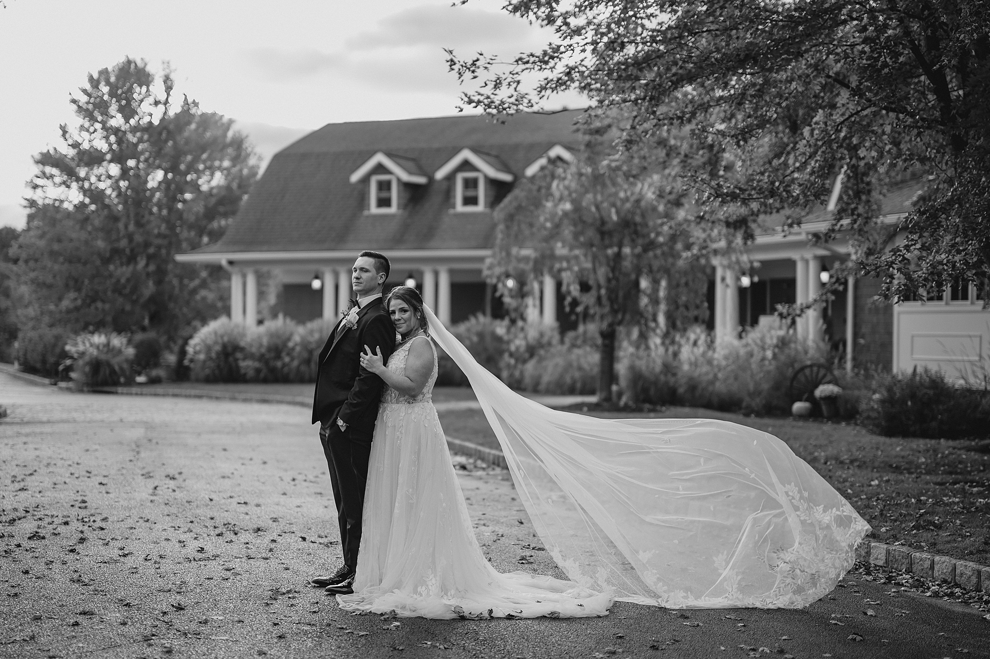 bride leans against groom's back with veil floating behind her 