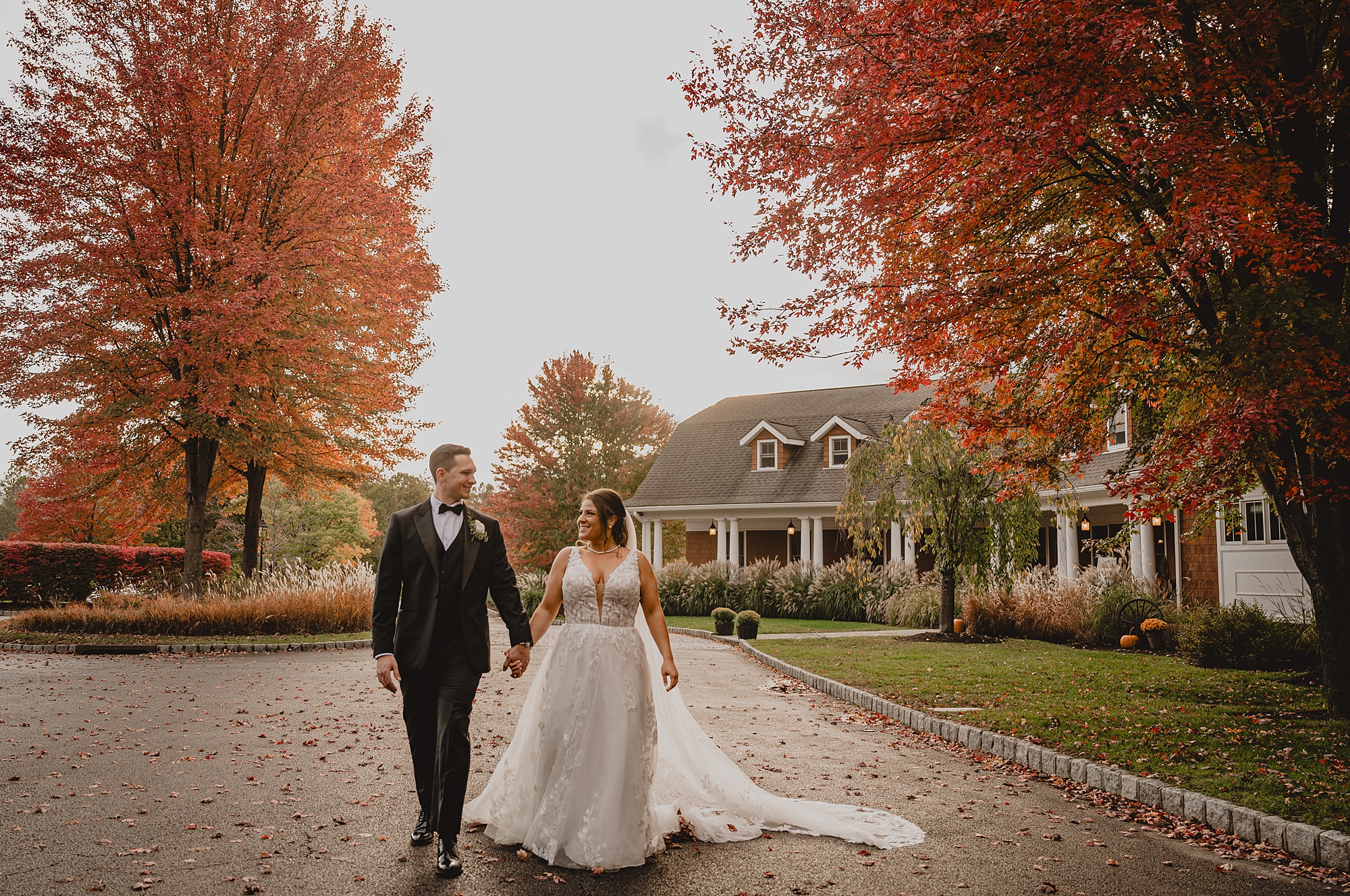 newlyweds hold hands walking down driveway at Hollow Brook Golf Club