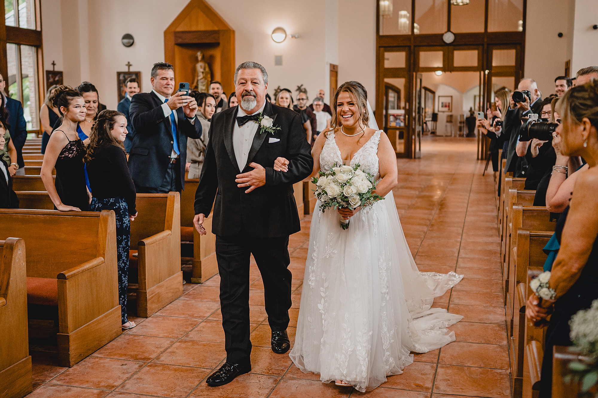 bride smiles walking down aisle with father during traditional church ceremony in New York