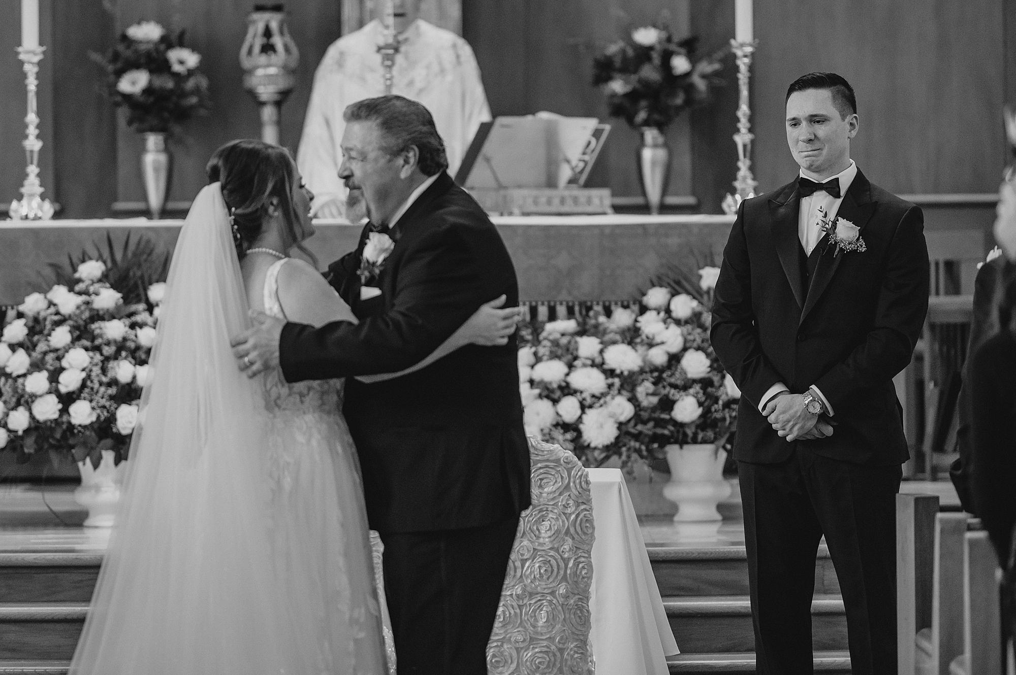 father hugs bride at the end of the aisle during traditional church ceremony in New York
