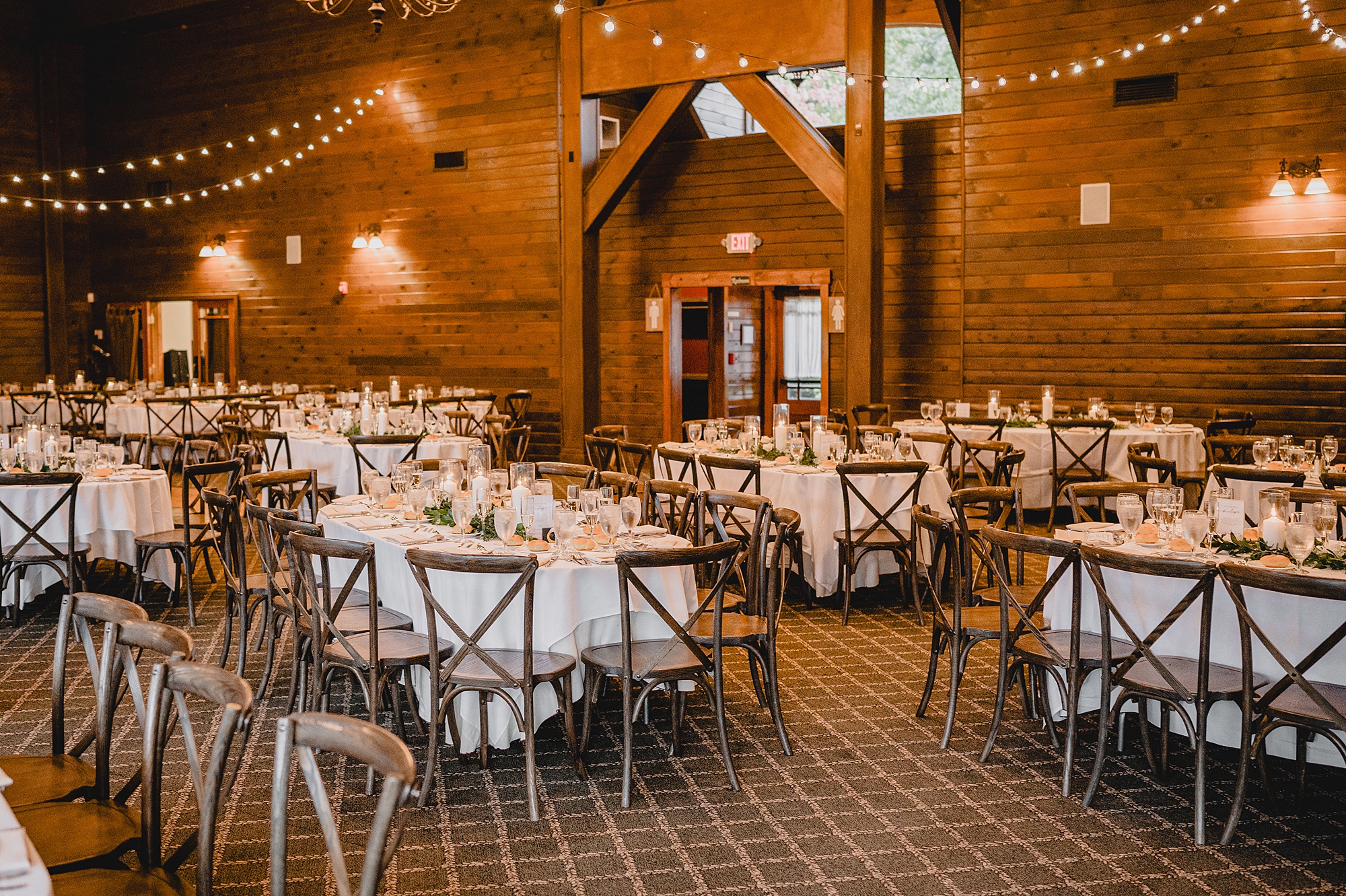 wedding reception setup with wood chairs and white details at Hollow Brook Golf Club