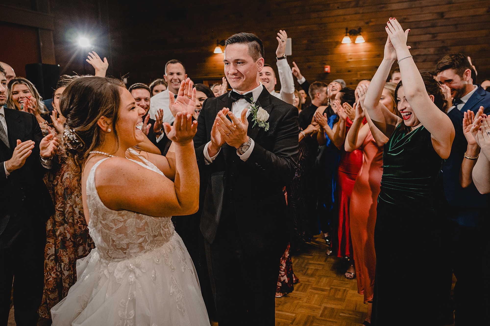 bride and groom clap with guests on dance floor