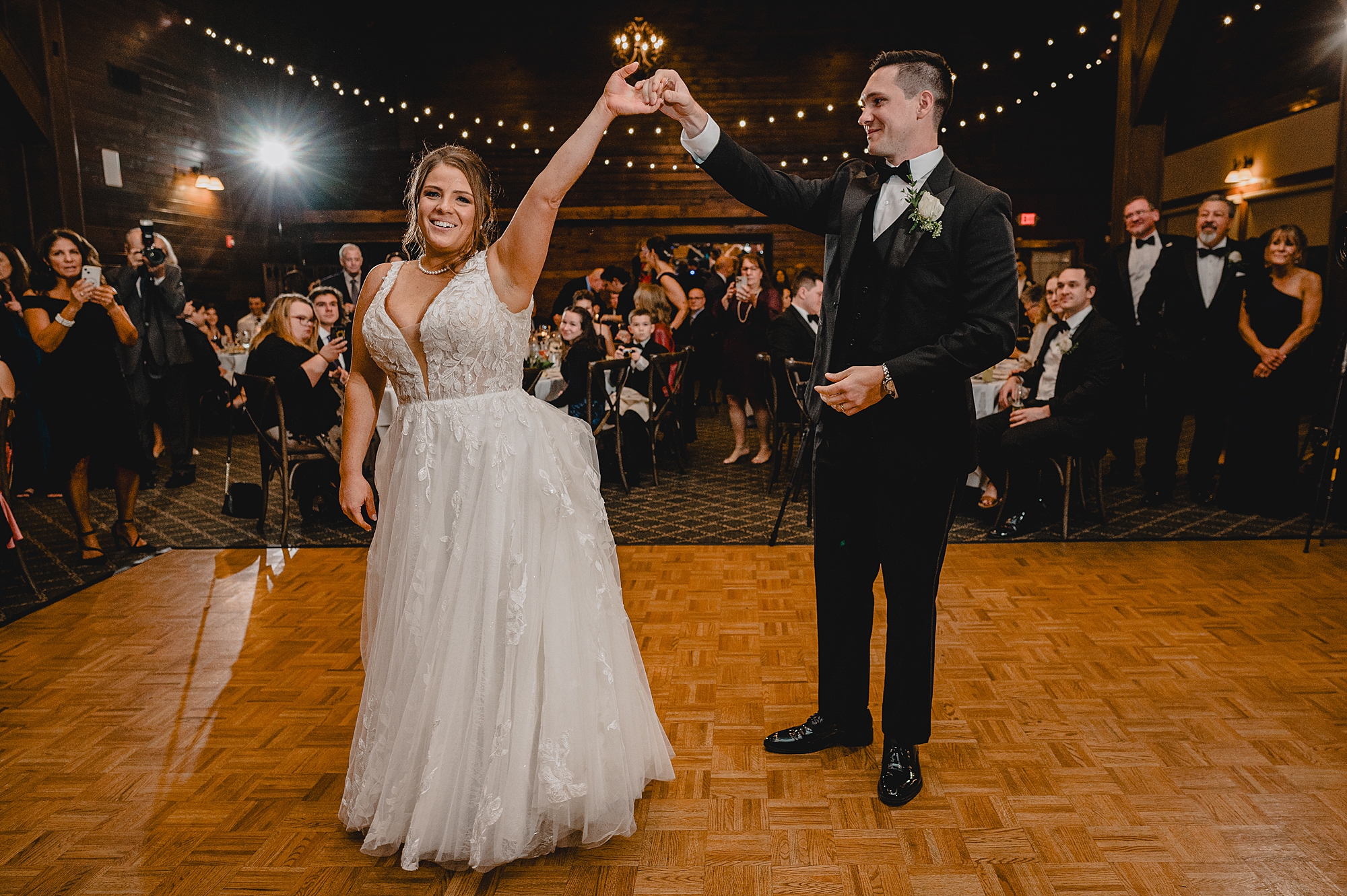 groom twirls bride showing her off to guests 