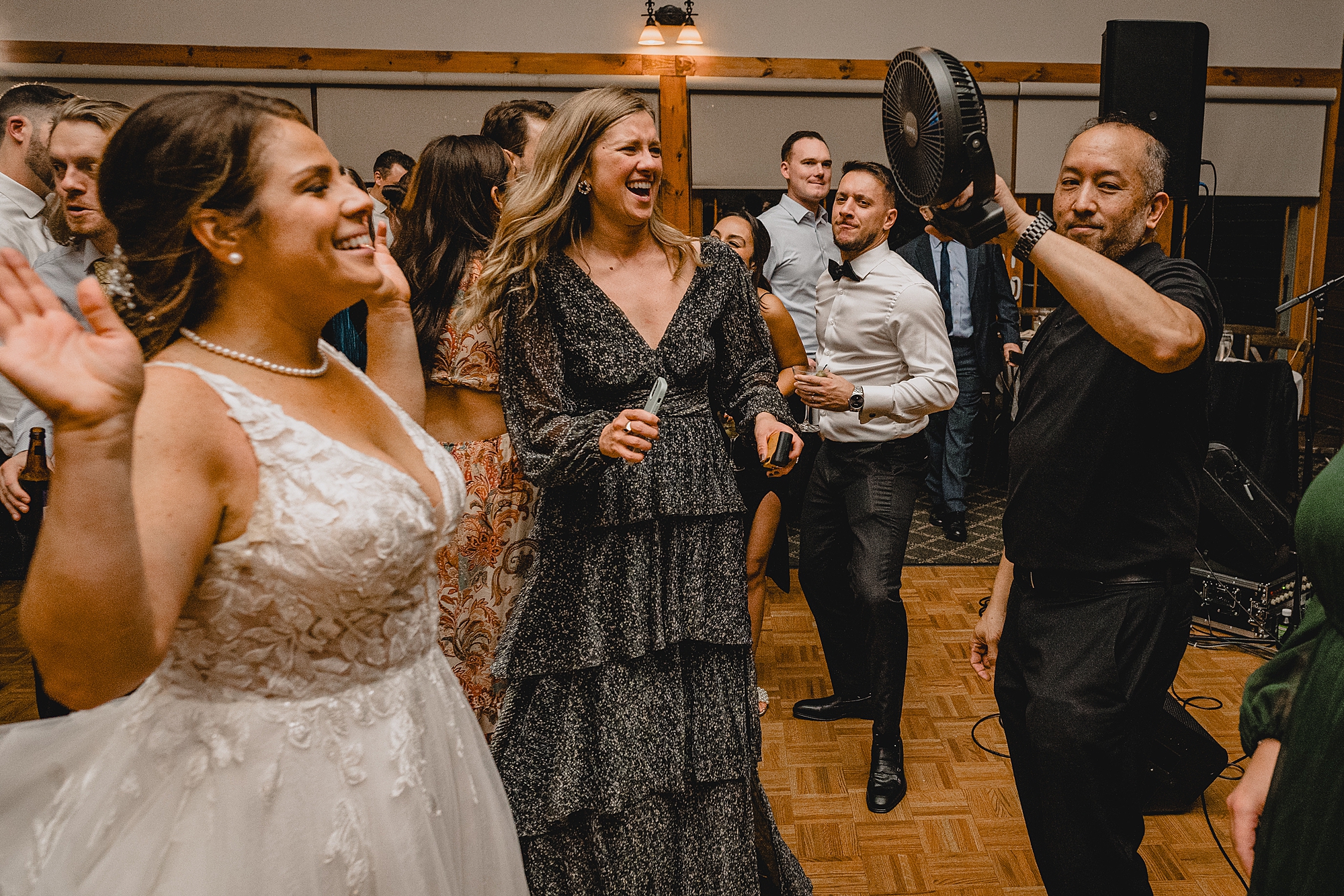 musician holds up fan on bride during reception 