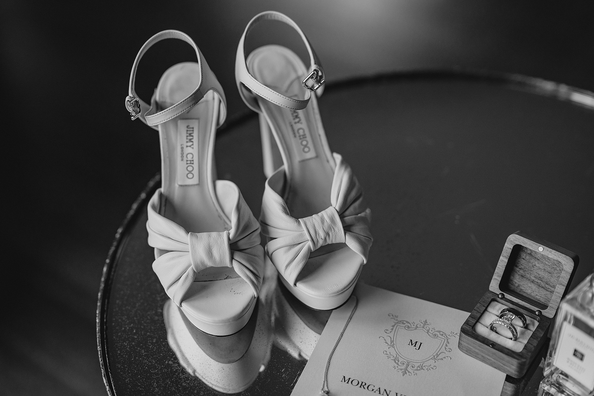 bride's white shoes with bows sit by invitations suite 