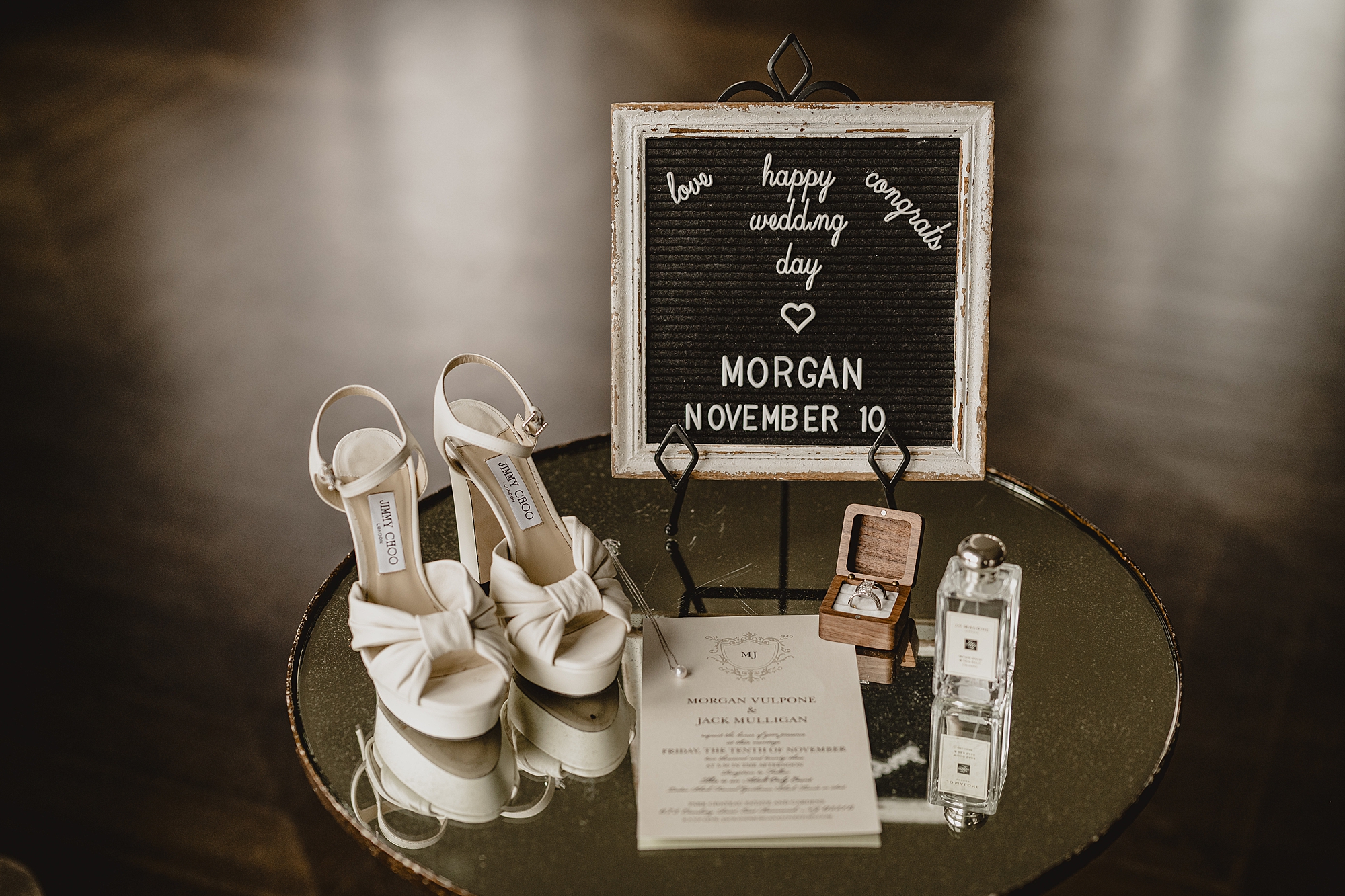 bride's shoes, invitations, jewelry box, and perfume sit under lettered sign