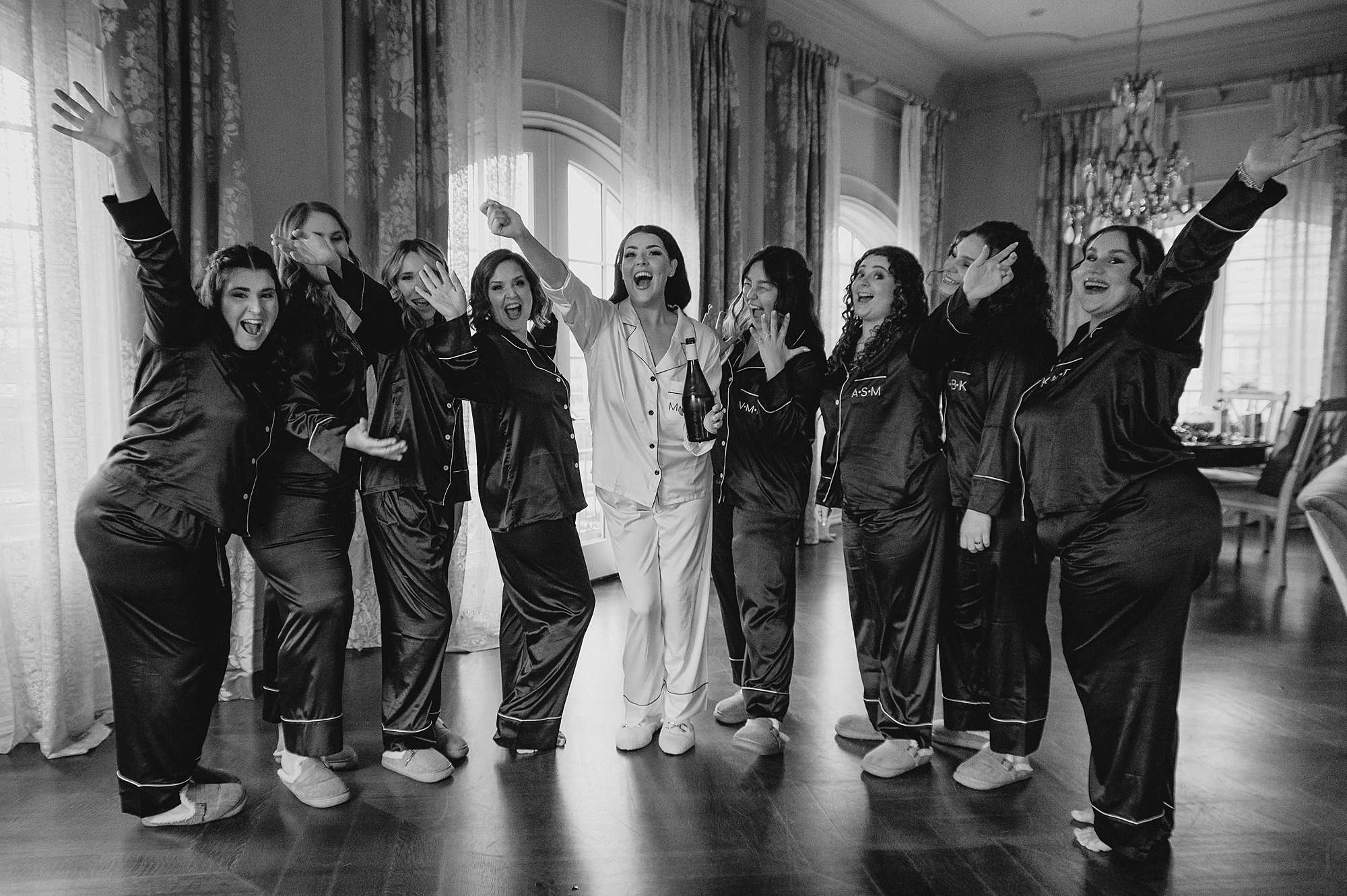 bride and bridesmaids stand in matching pajamas cheering in bridal suite at Park Chateau