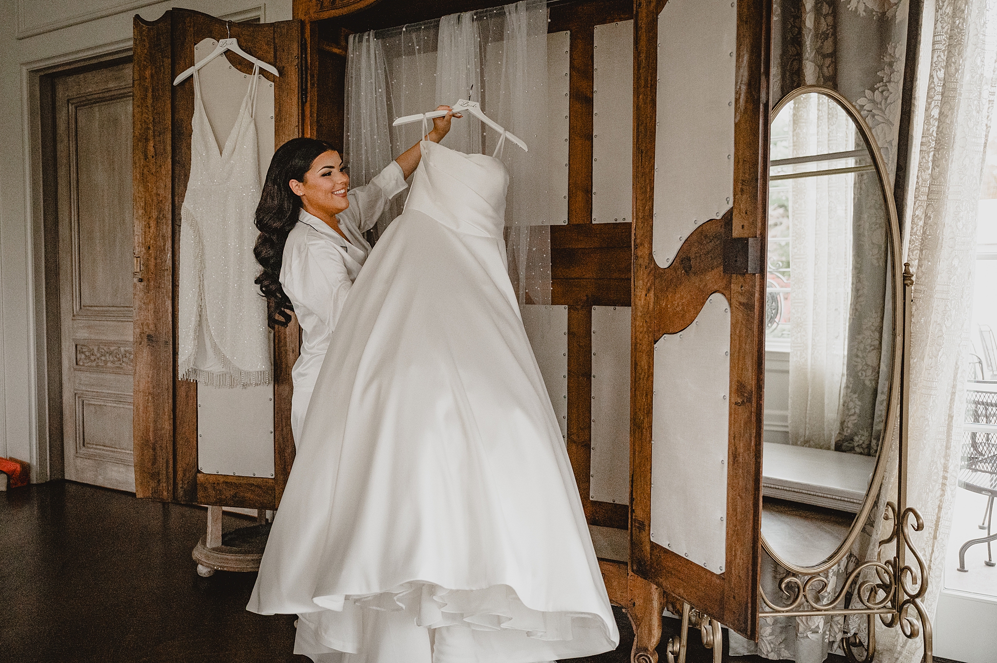 bride looks at wedding dress in armoire in suite at Park Chateau