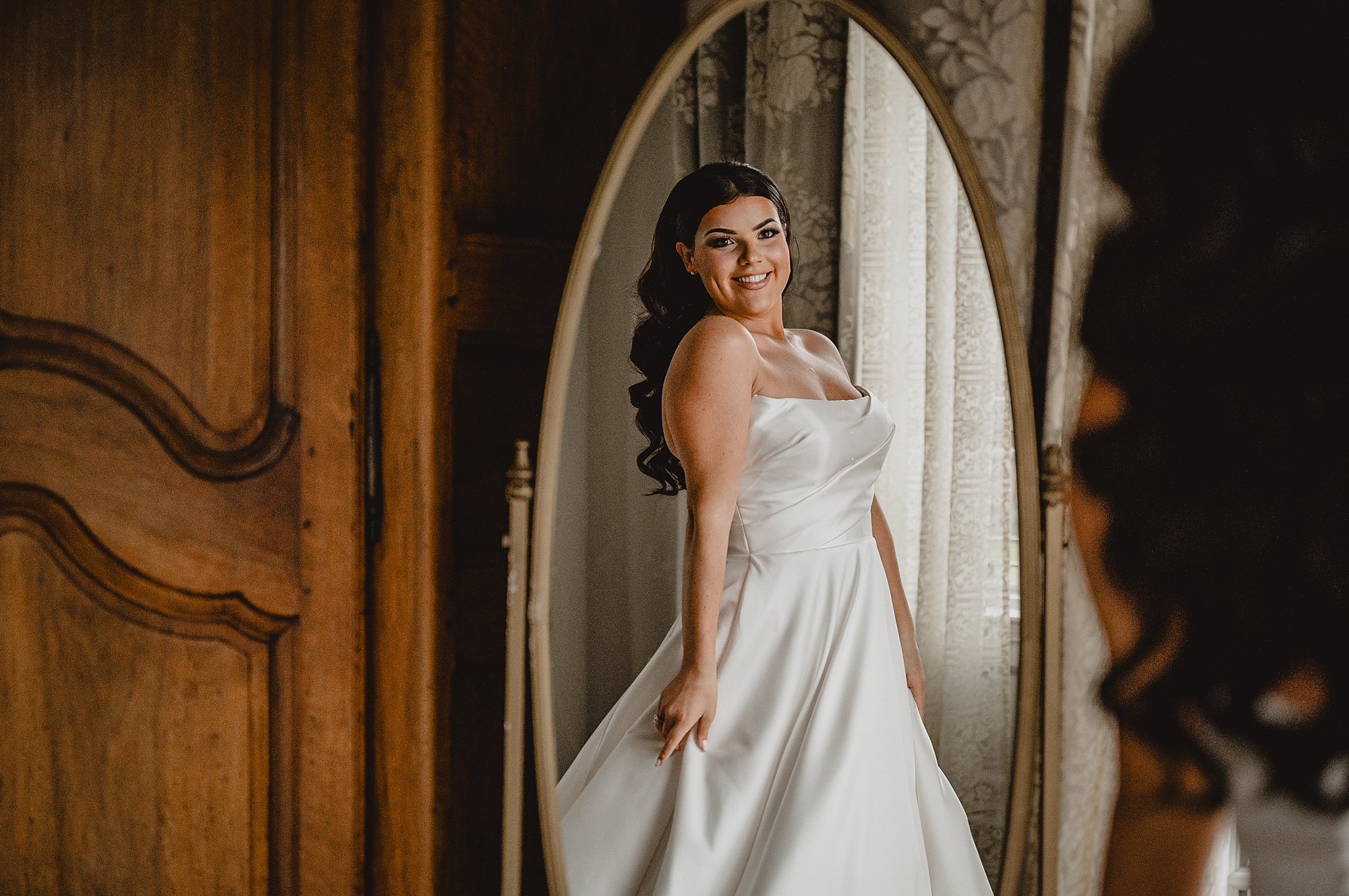bride smiles twirling in strapless wedding gown in mirror at Park Chateau