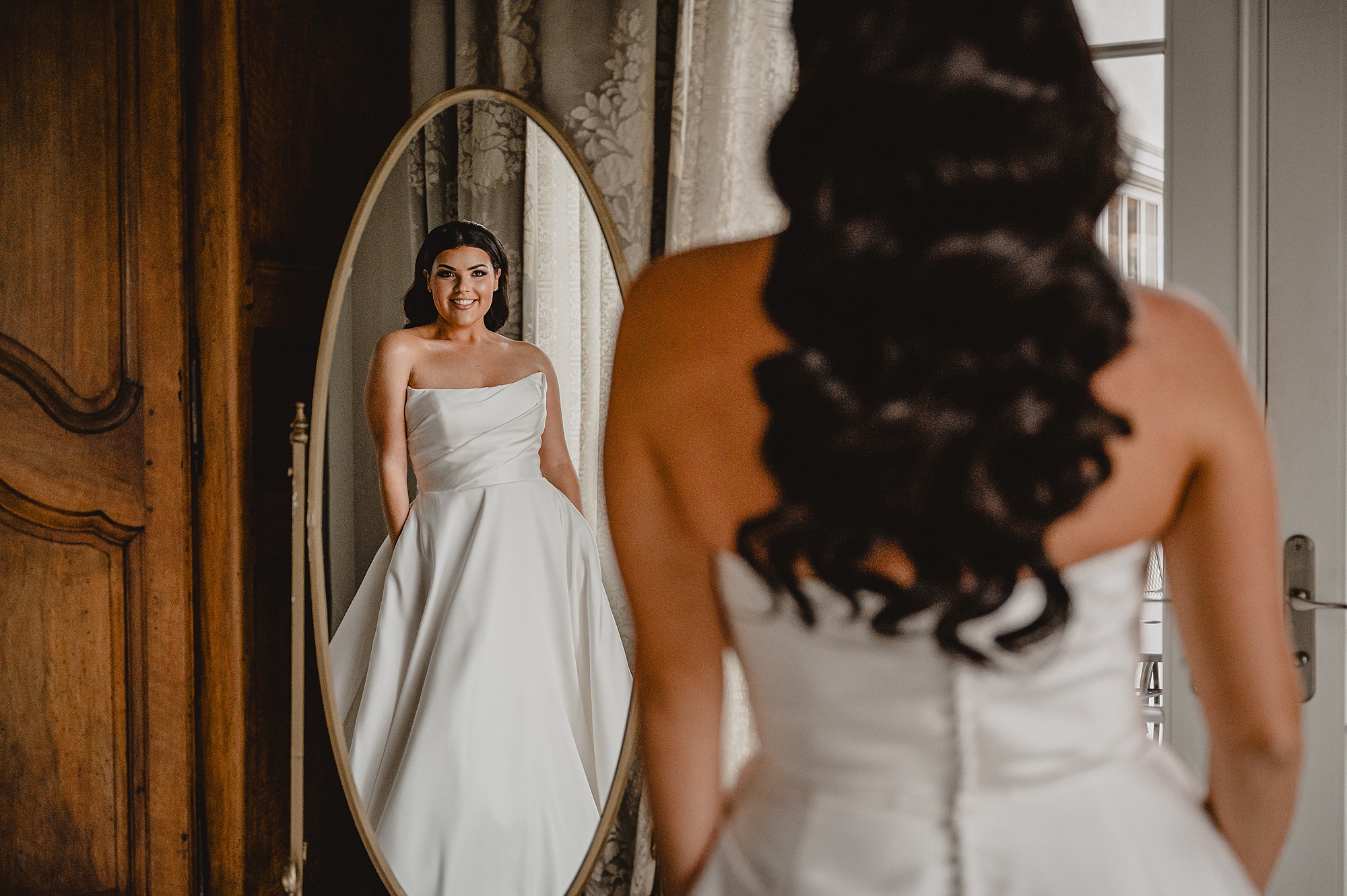bride grins at reflection in mirror during prep in bridal suite at Park Chateau