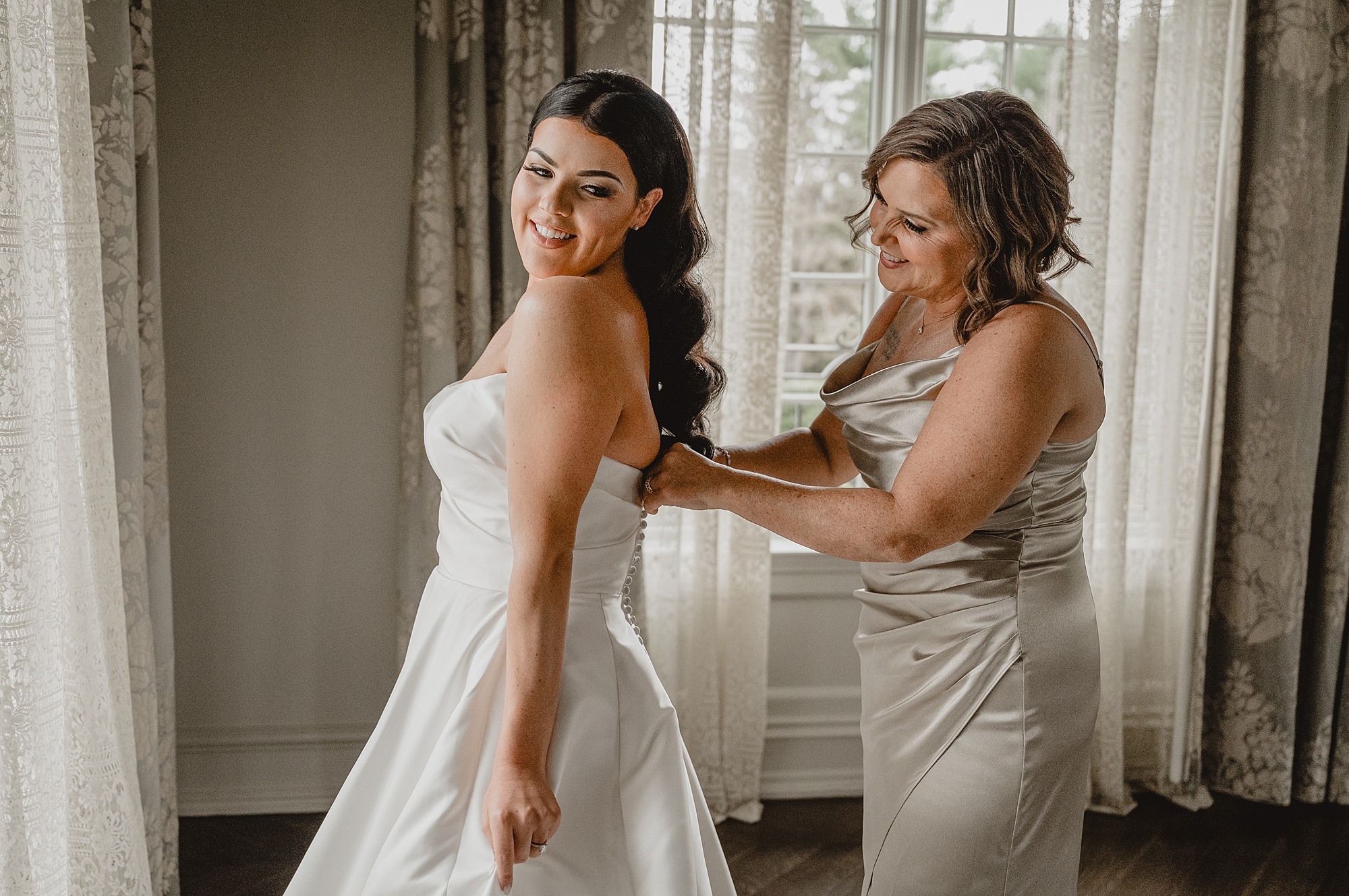 mother helps bride into wedding dress in bridal suite at Park Chateau