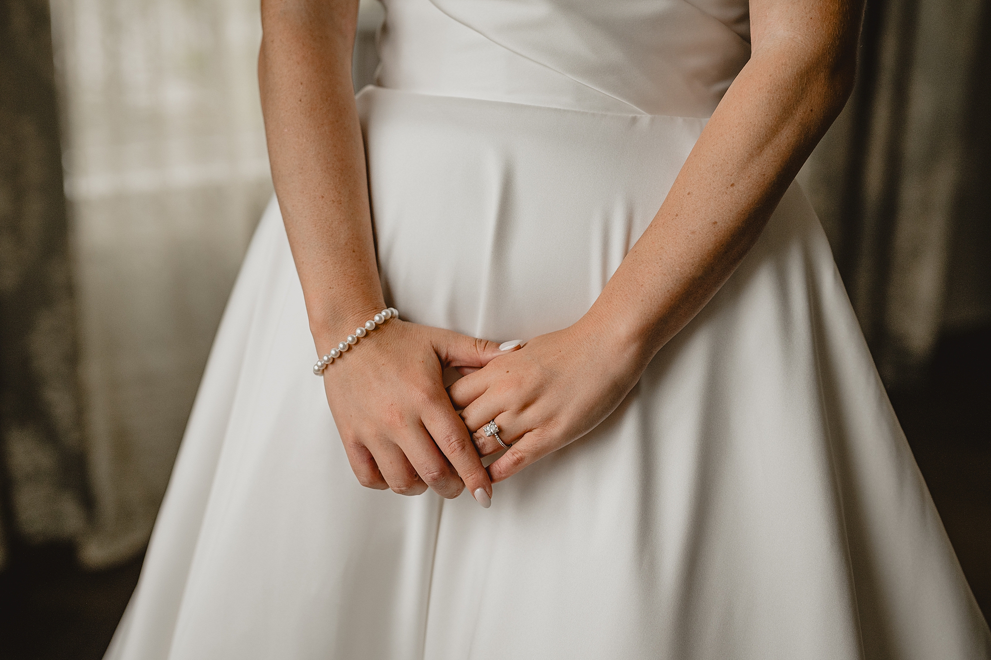 bride clasps hands together showing off pearl bracelet 
