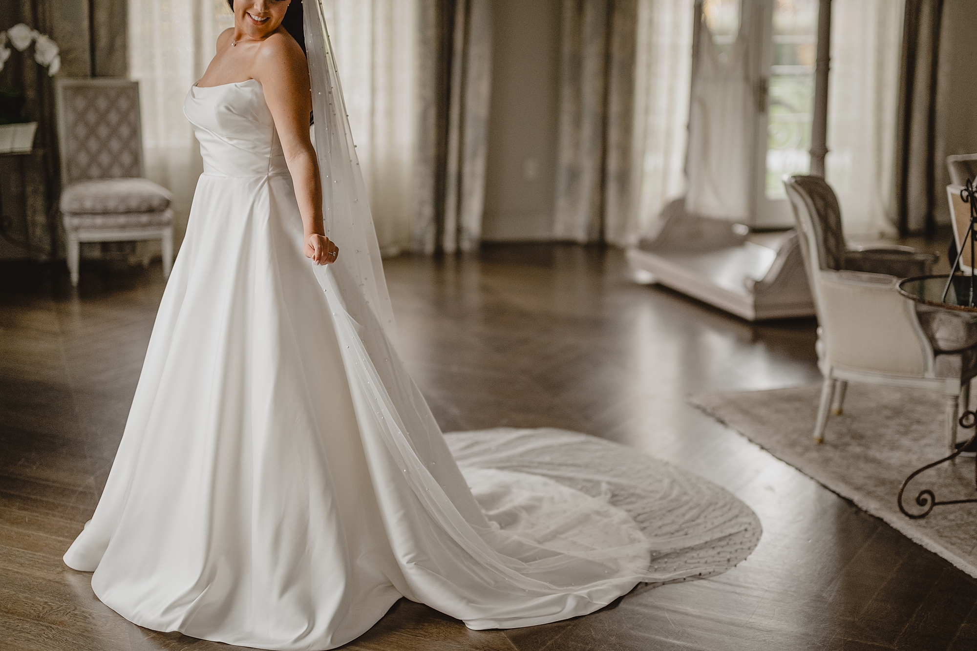 bride holds veil around shoulders in strapless gown of bridal suite at Park Chateau