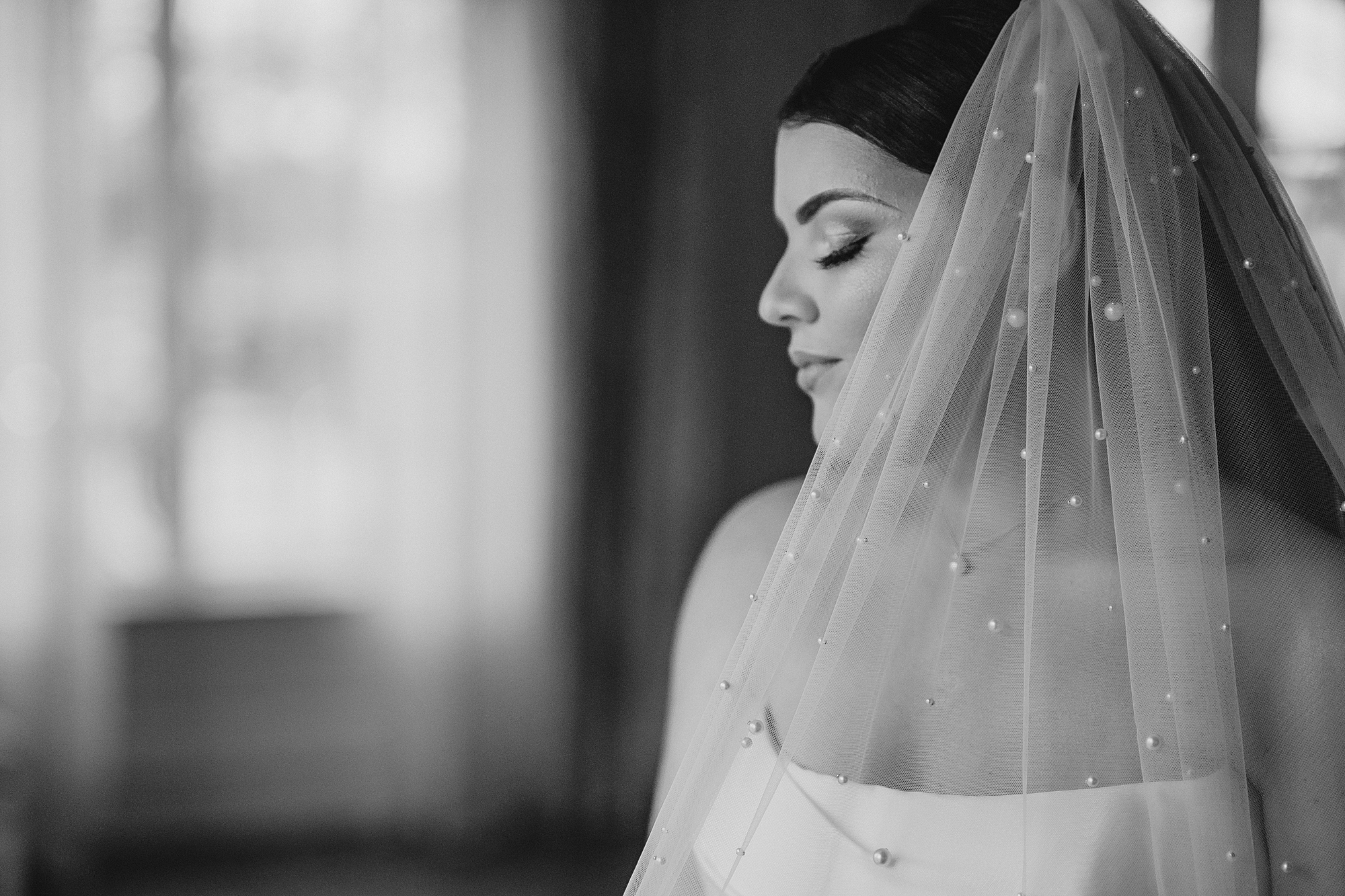 bride closes eyes smiling with veil around shoulders 