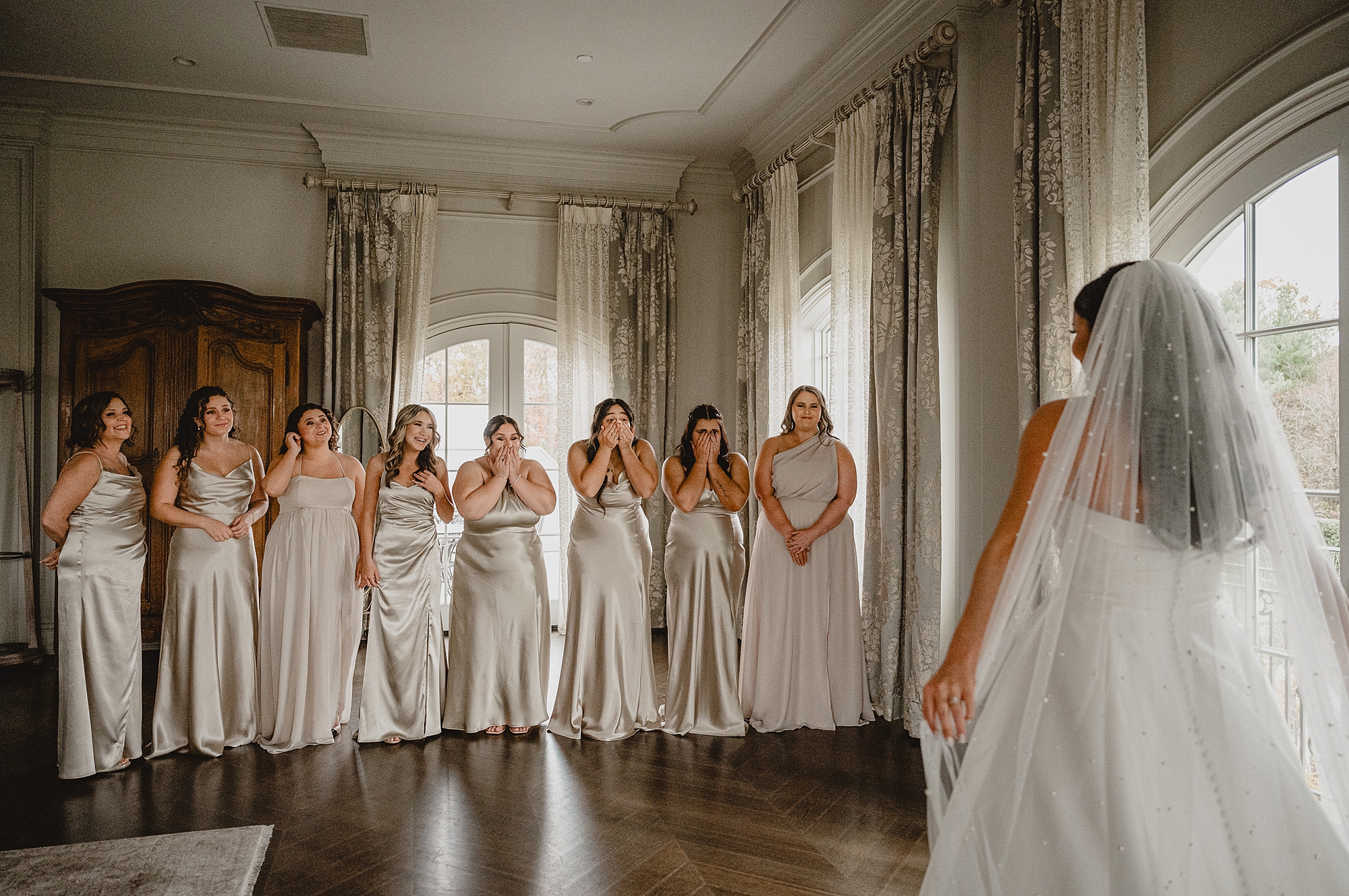 bride shows bridesmaids wedding gown during first look in bridal suite at Park Chateau