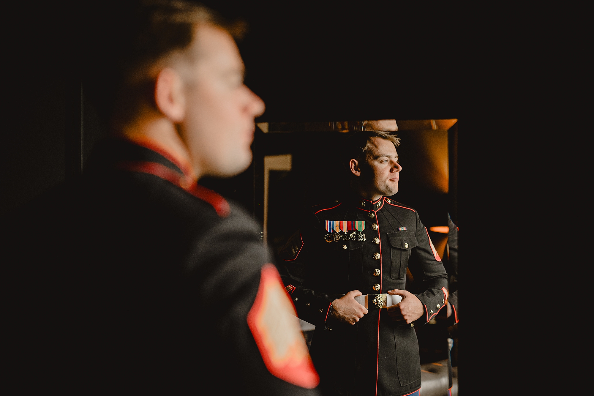 groom adjusts belt on Marines uniform on wedding day 
