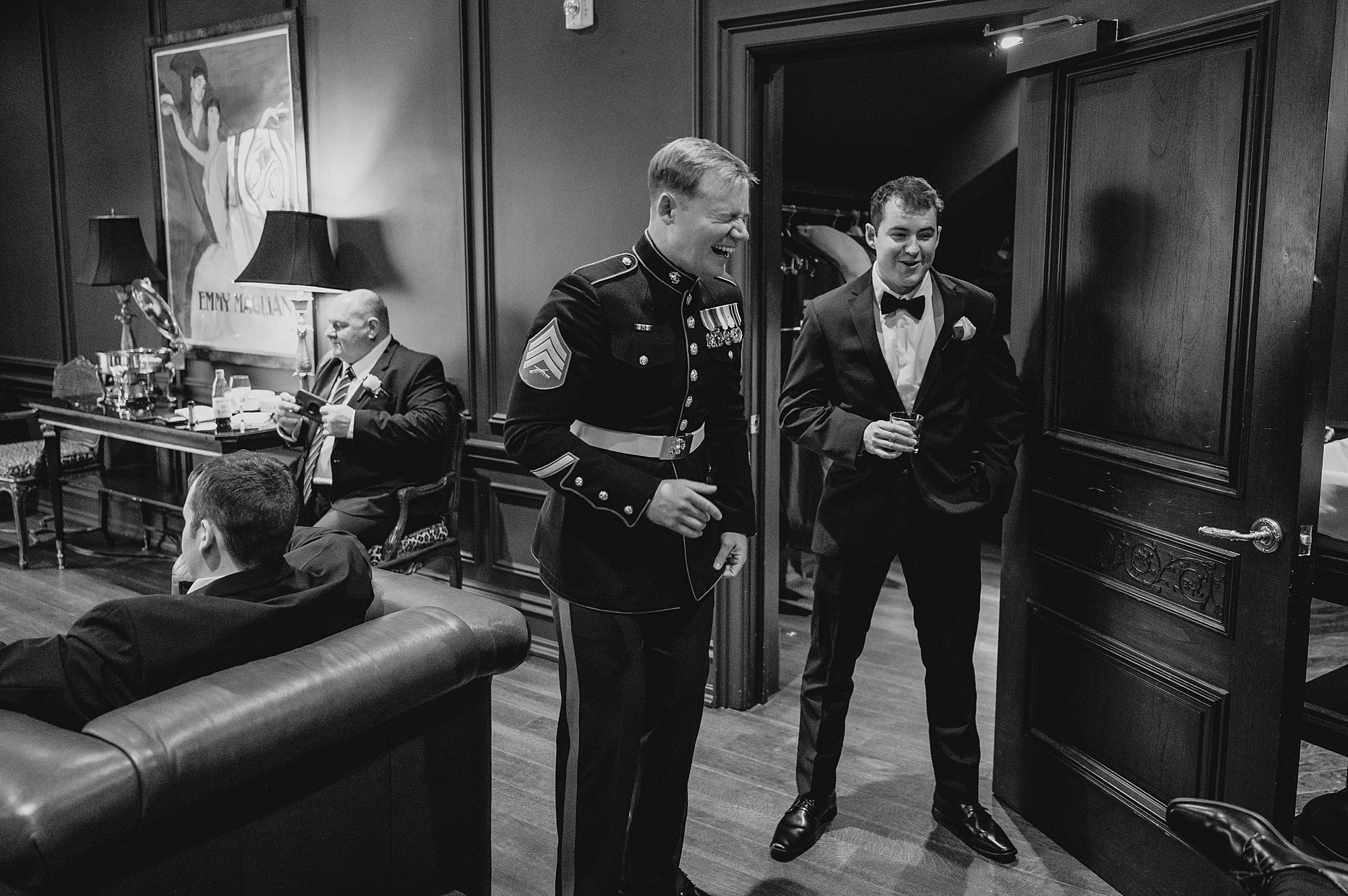 groom in military uniform laughs with groomsmen in prep space