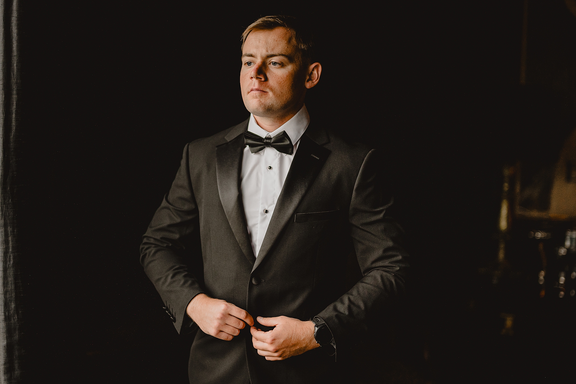 groom buttons up suit jacket during prep at Park Chateau