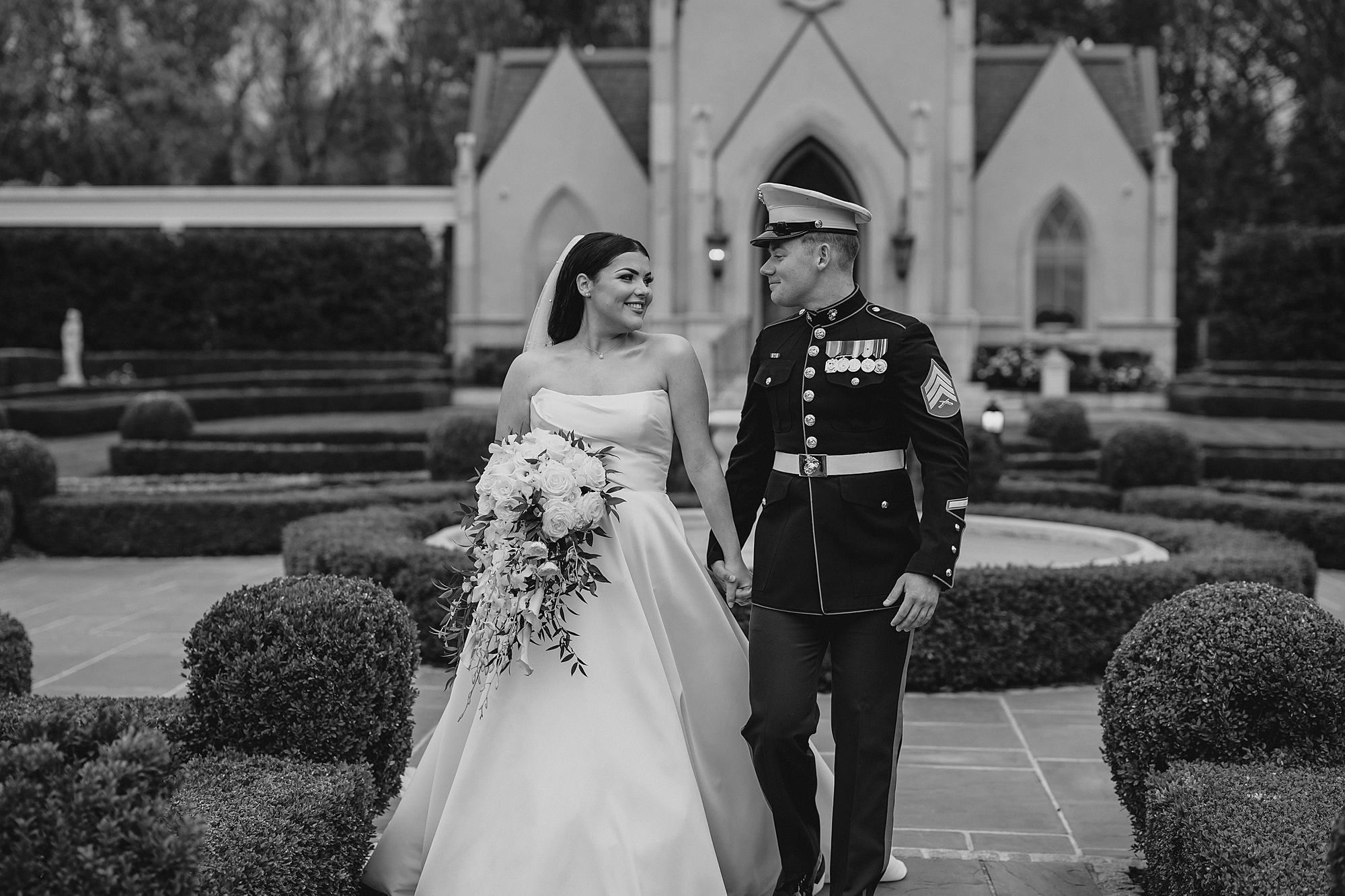 bride walks with Marine groom in front of chapel at Park Chateau