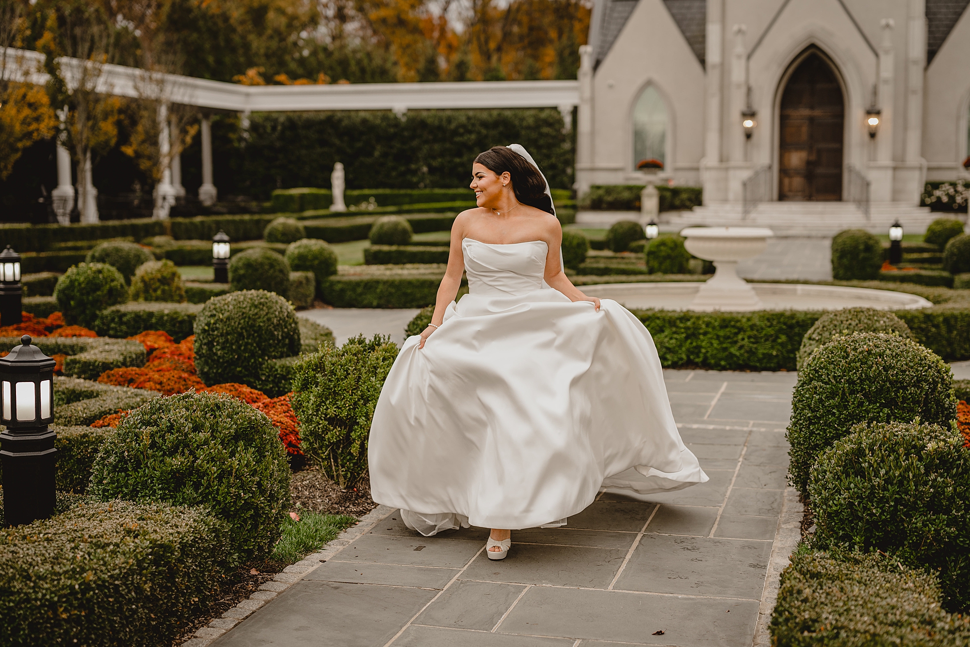 bride holds skirt of wedding gown running away from chapel 