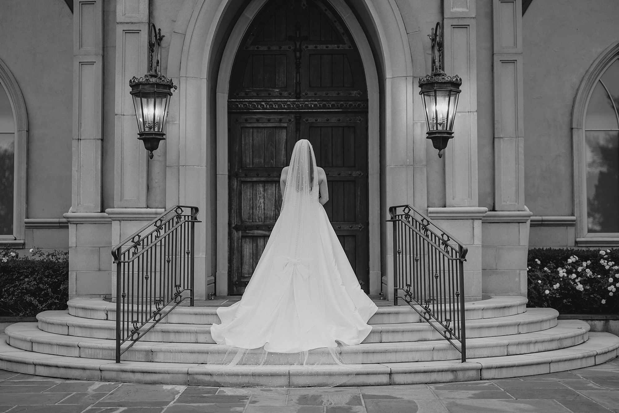 bride stands on steps of Park Chateau looking at wooden doors 