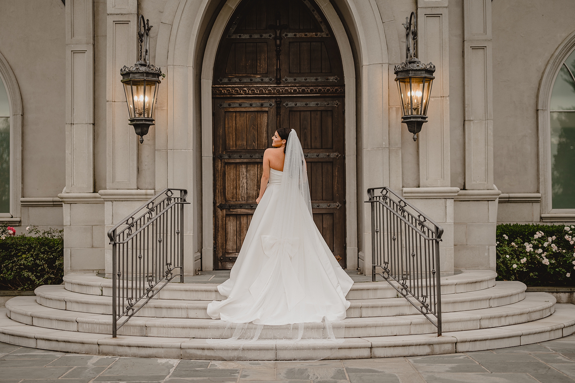 bride stands on steps of Park Chateau chapel looking over shoulder 