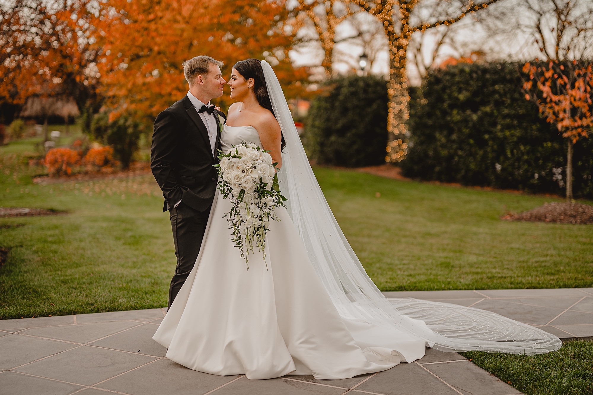 bride and groom stand on walkway with noses touching on fall wedding day at Park Chateau