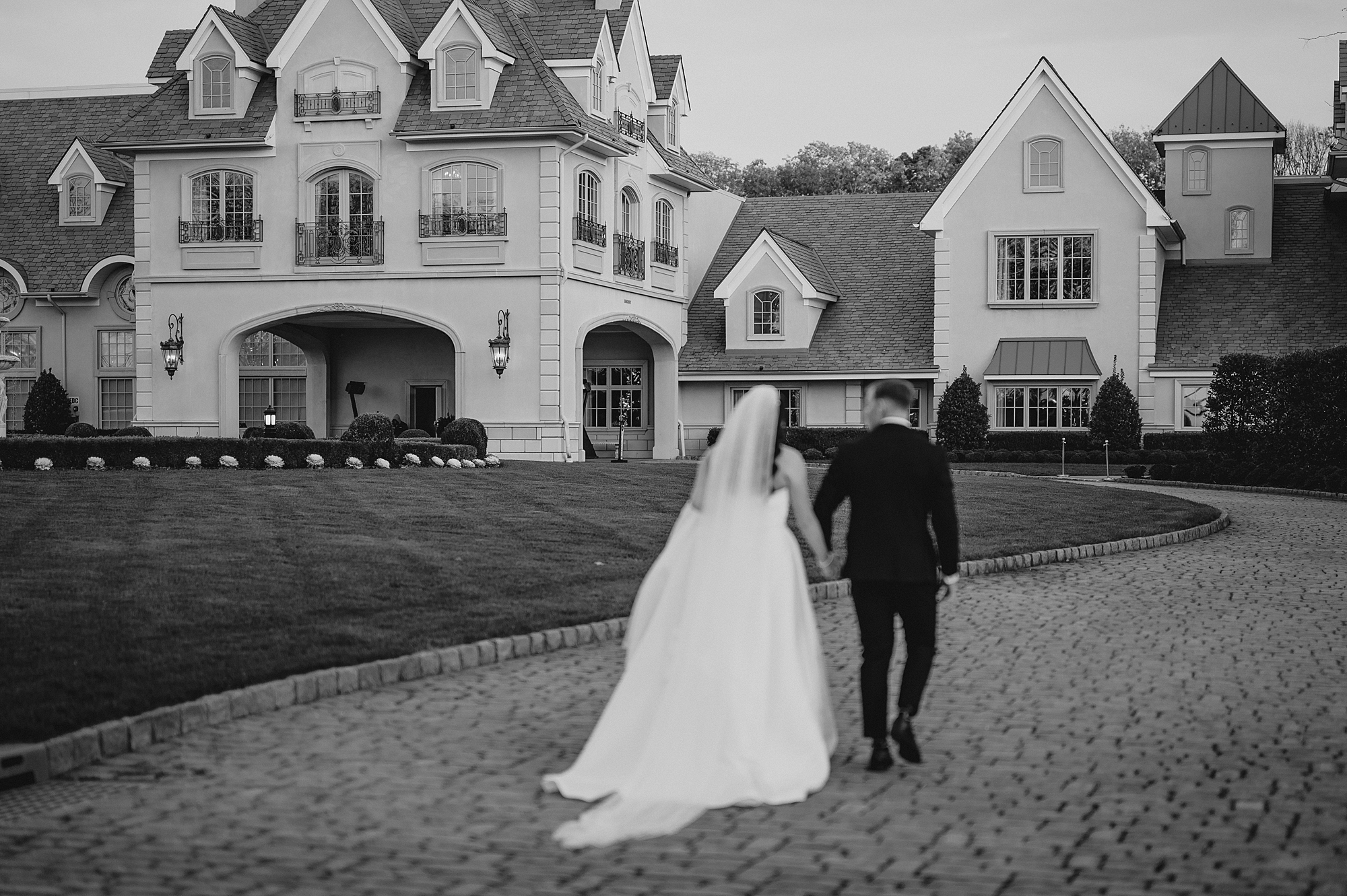 newlyweds walk towards Park Chateau Estate on driveway 