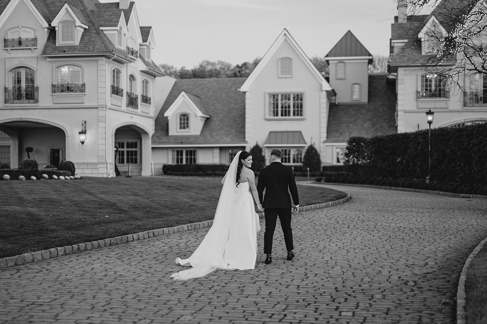 bride and groom hold hands walking towards Park Chateau Estate 
