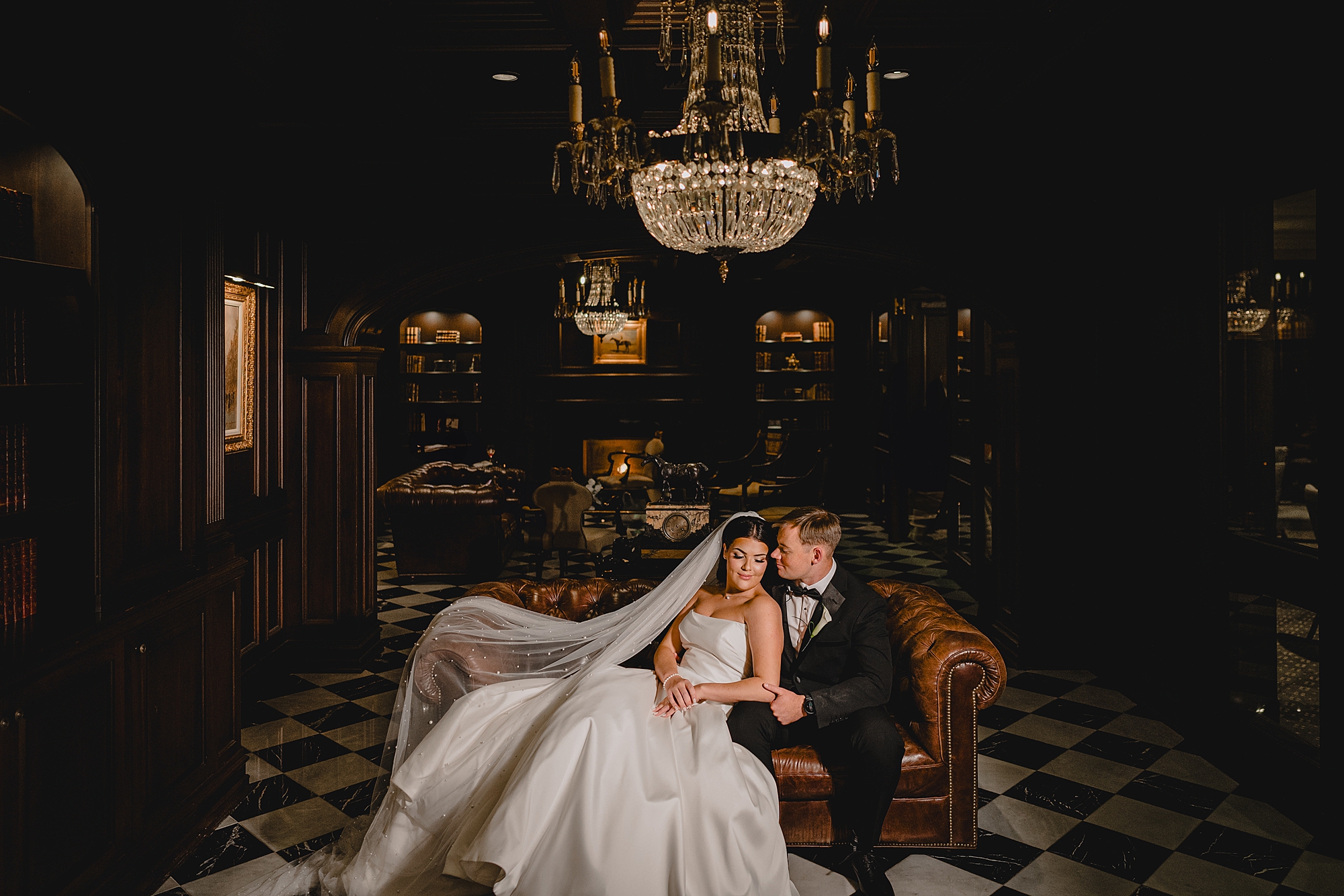 bride and groom snuggle on leather couch in library of Park Chateau Estate 
