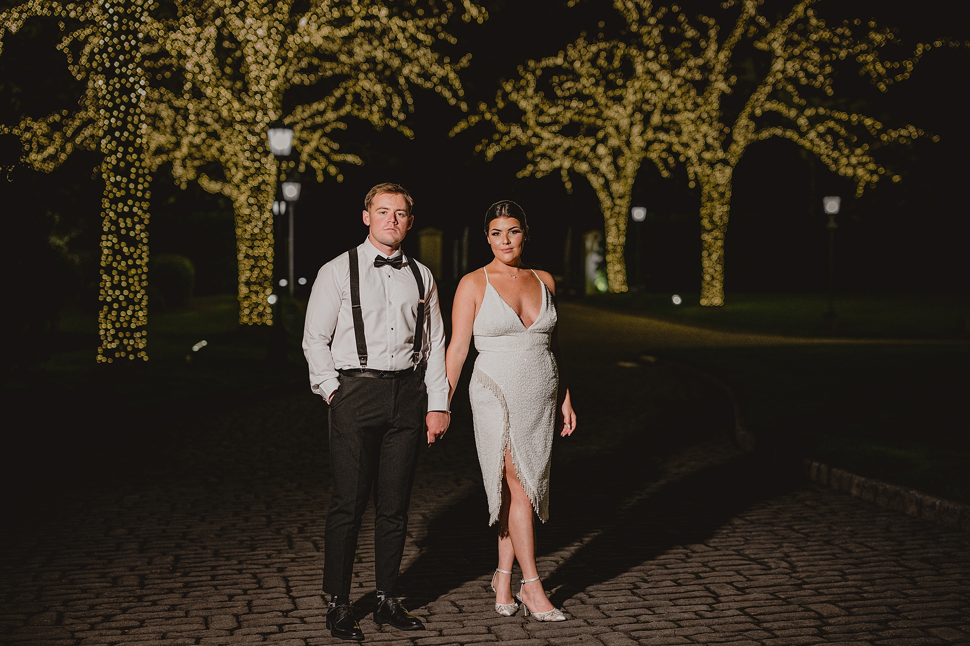 bride and groom hold hands on driveway lined with trees at Park Chateau