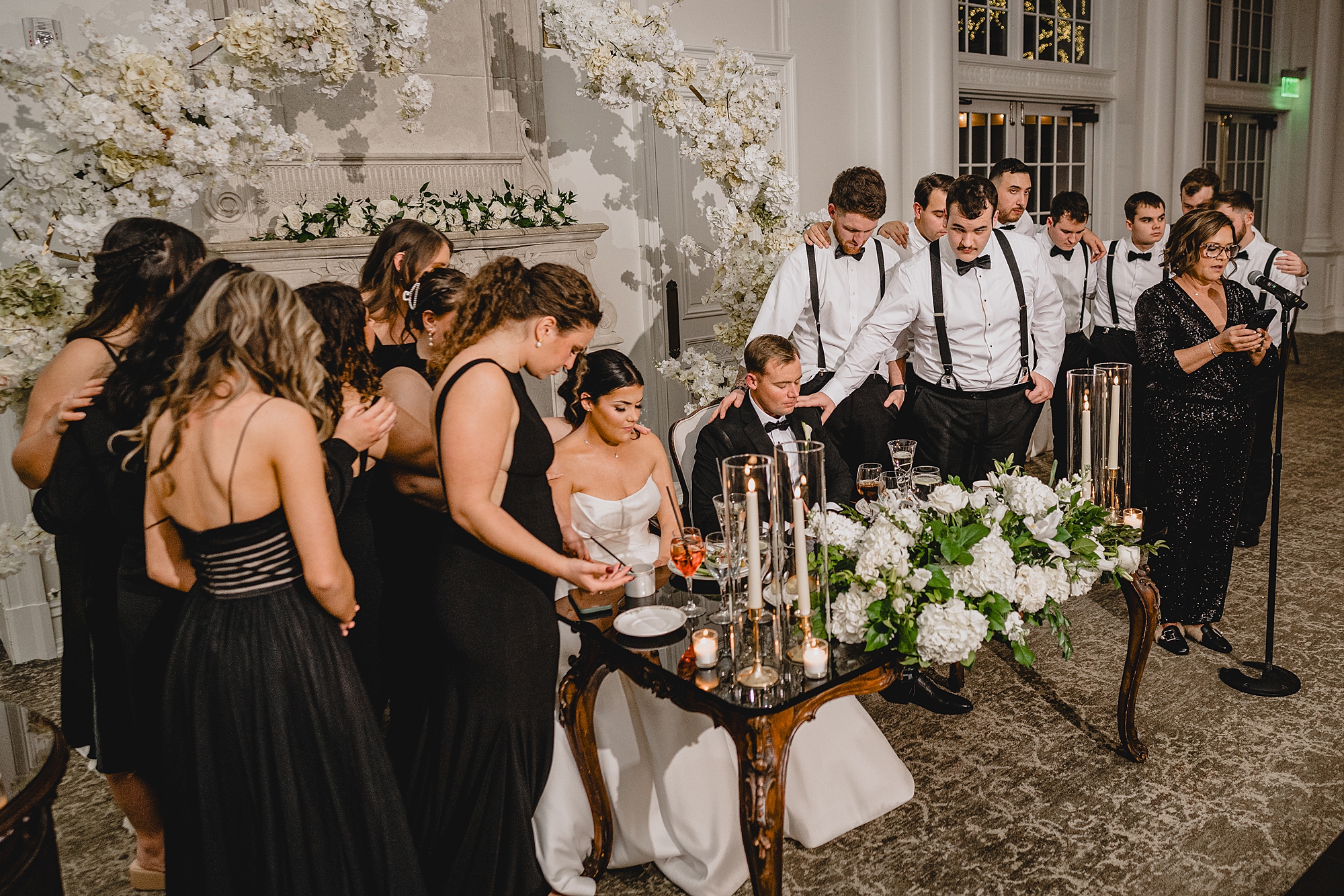 bride and groom pray with wedding party around them in front of fireplace at Park Chateau Estate