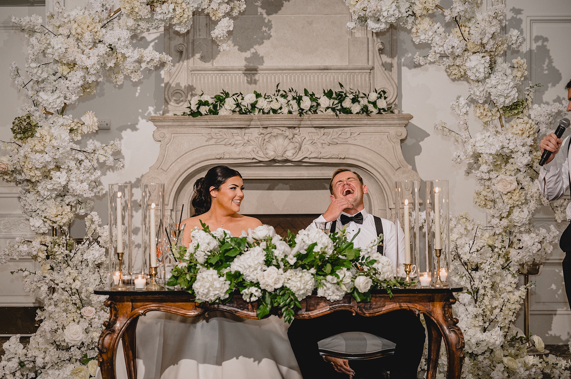 newlyweds laugh sitting at sweetheart table during fall wedding reception 