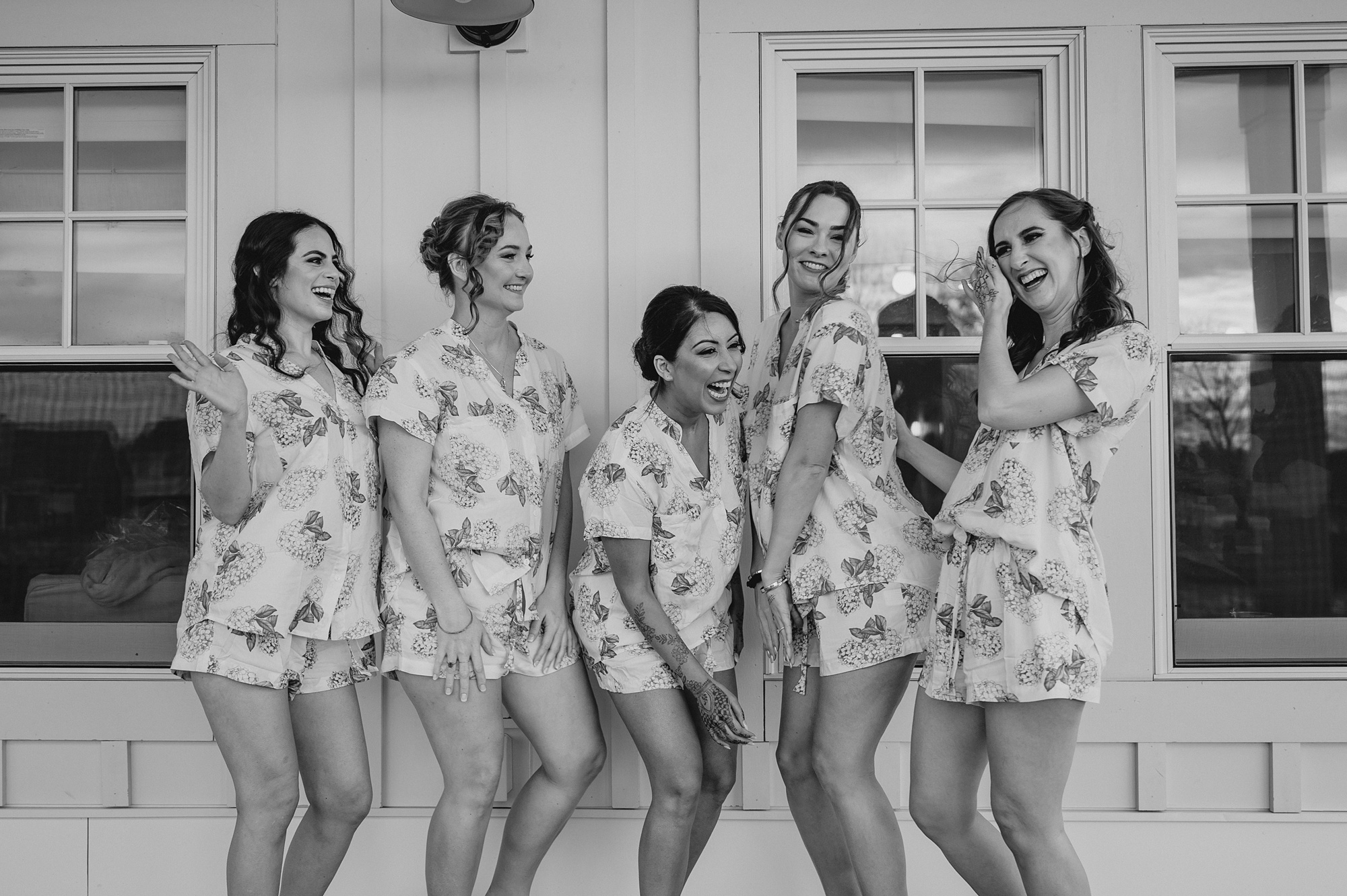 bride and bridesmaids pose in floral pajamas outside the Lake House at Canandaigua