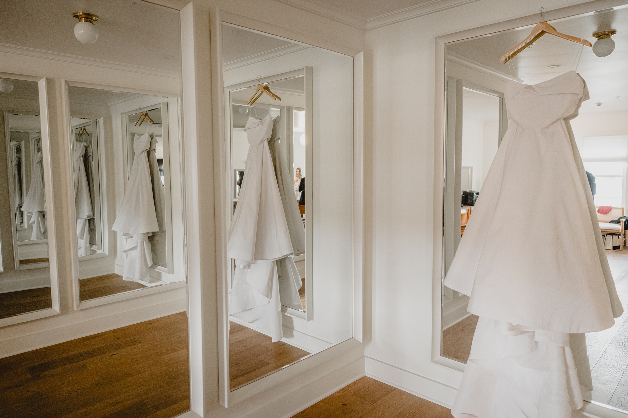 wedding dress hangs in front of mirrored closet