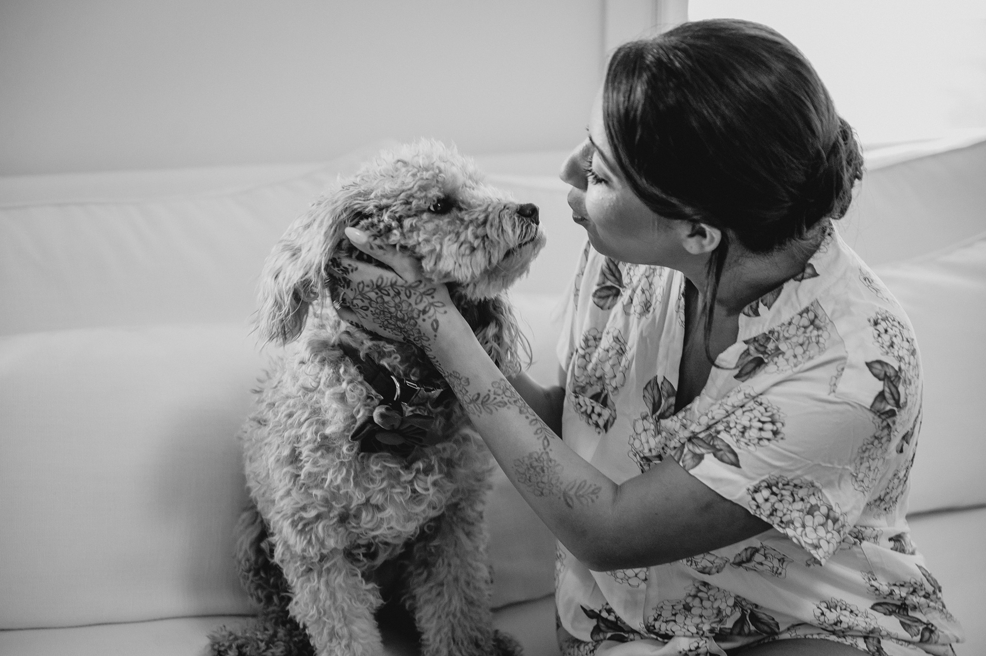 woman in floral pajamas leans to kiss dog on the nose 