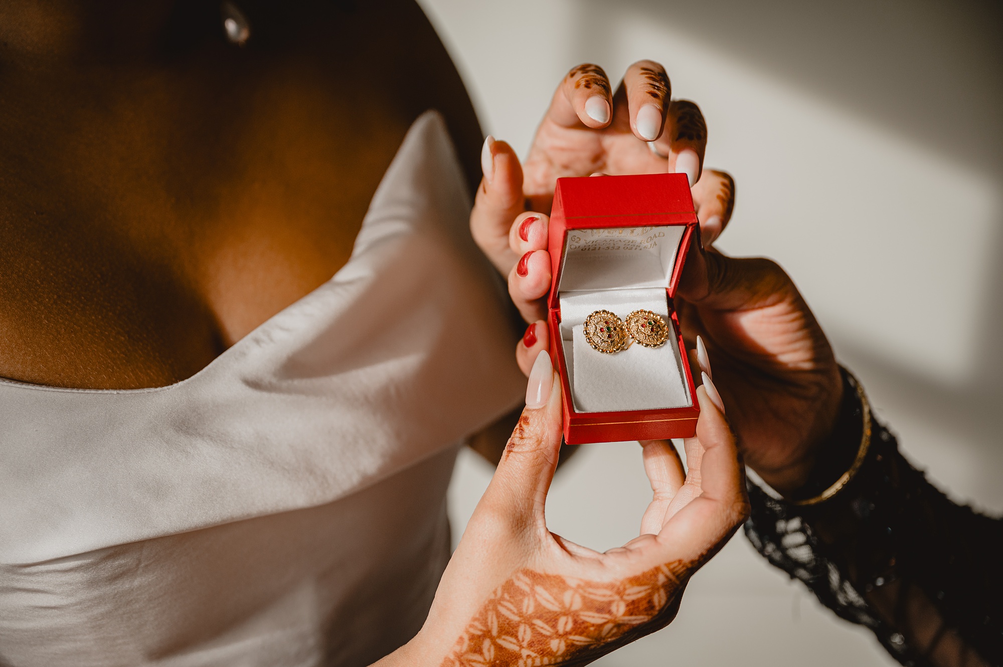 bride opens jewelry box to show bridesmaid earrings 