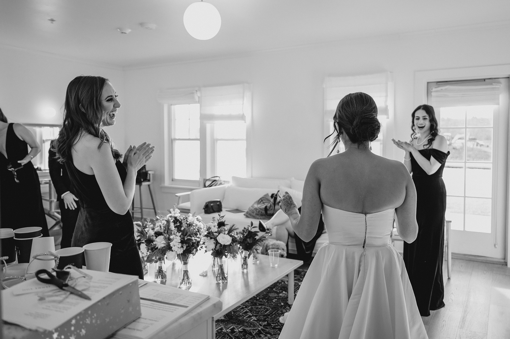 bridesmaids stand with bride around counter looking at bouquets 