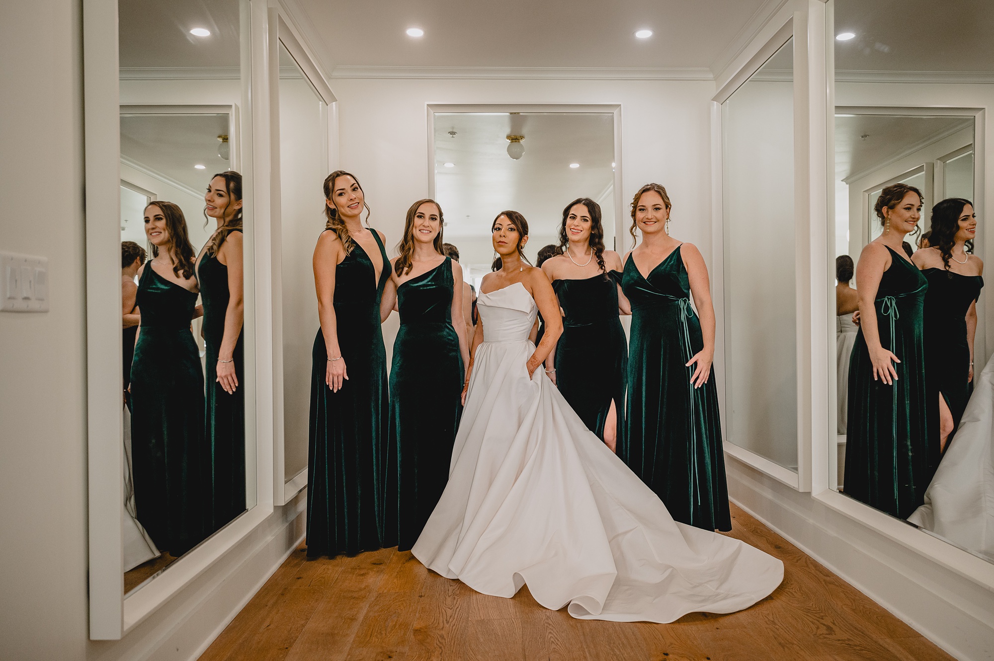 bride stands with bridesmaids in emerald gowns at the Lake House at Canandaigua