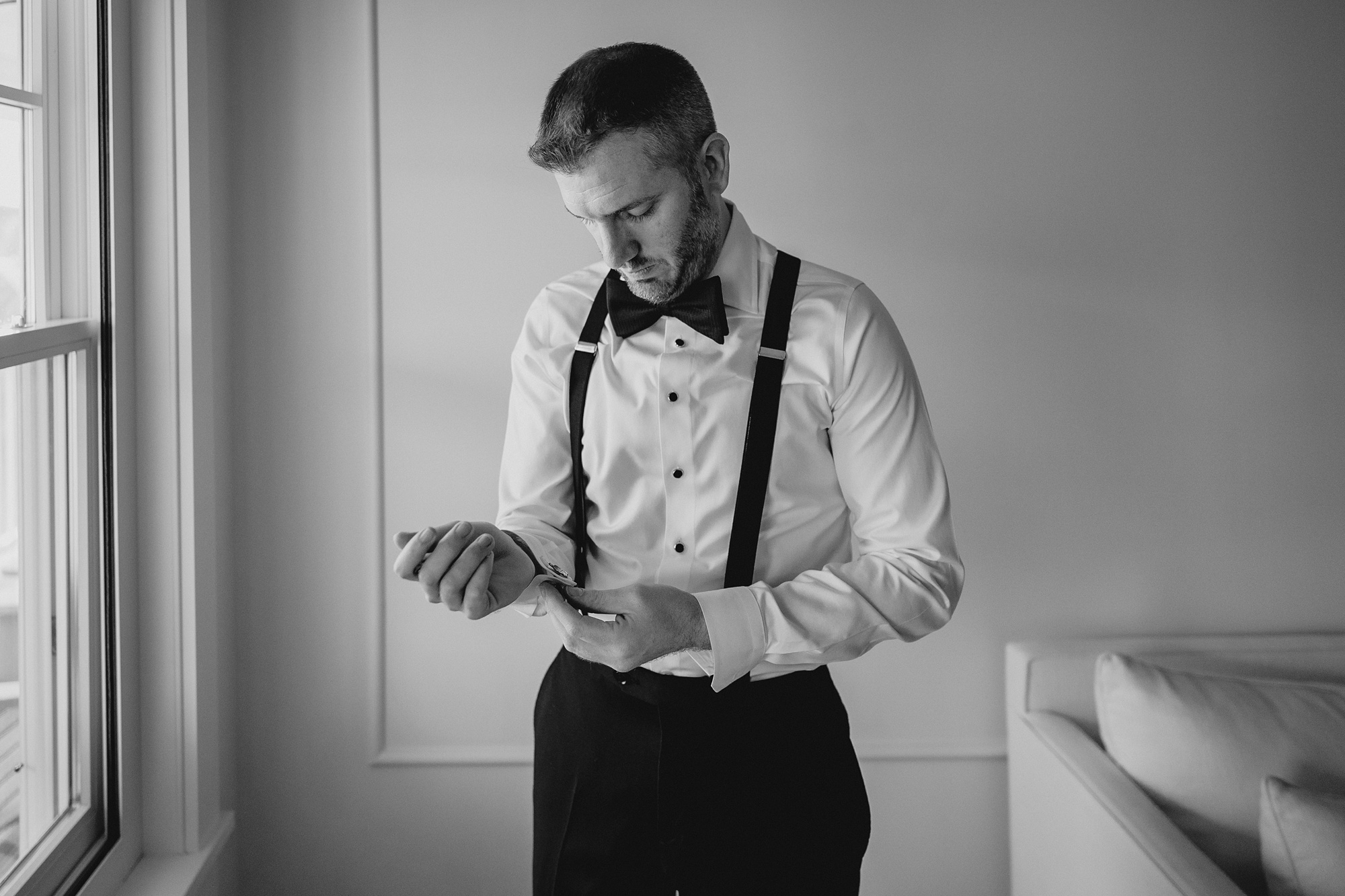 groom adjusts cufflinks on white shirt before NJ wedding 