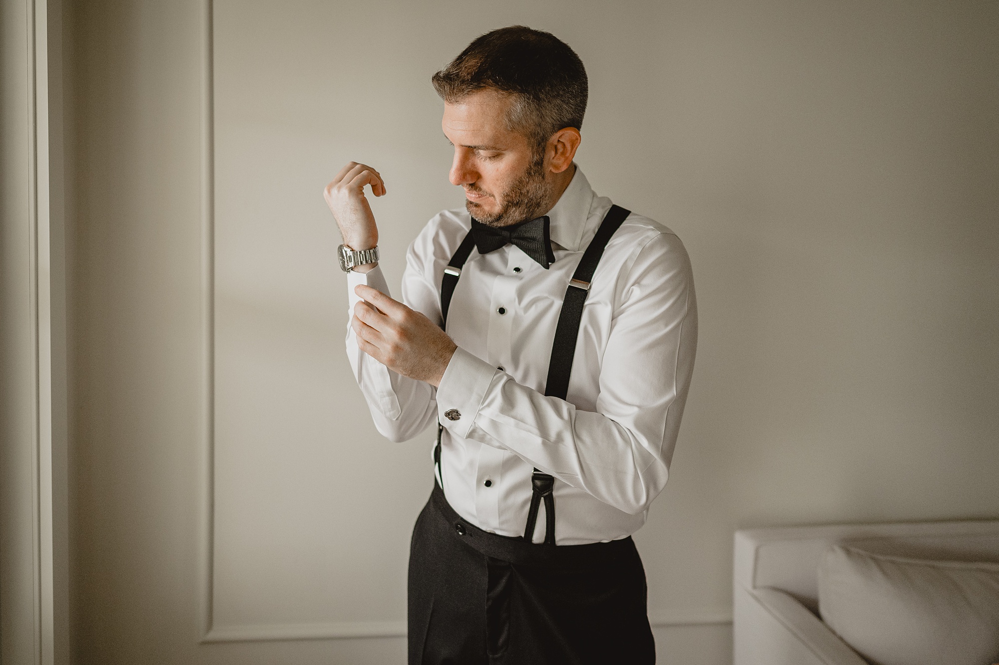 groom adjusts cufflinks while preparing for NJ wedding day 