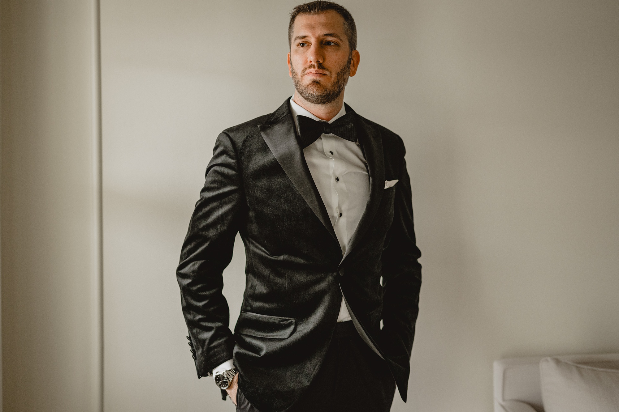 groom poses with hands in pockets of black suit 