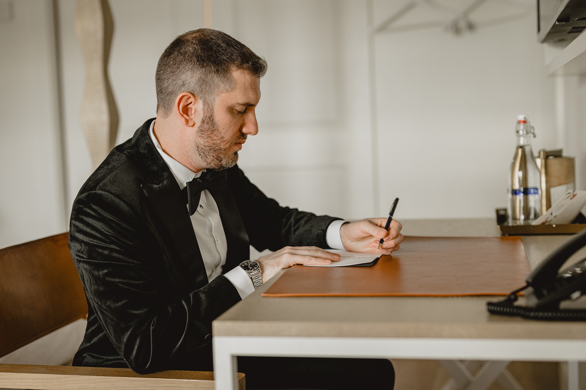 groom signs letter to bride on the morning of his wedding