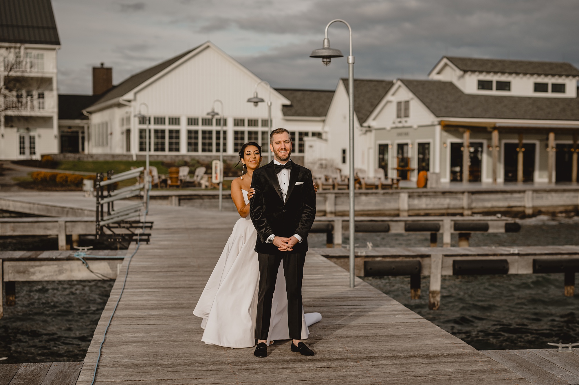 bride approaches groom on the dock at the Lake House at Canandaigua