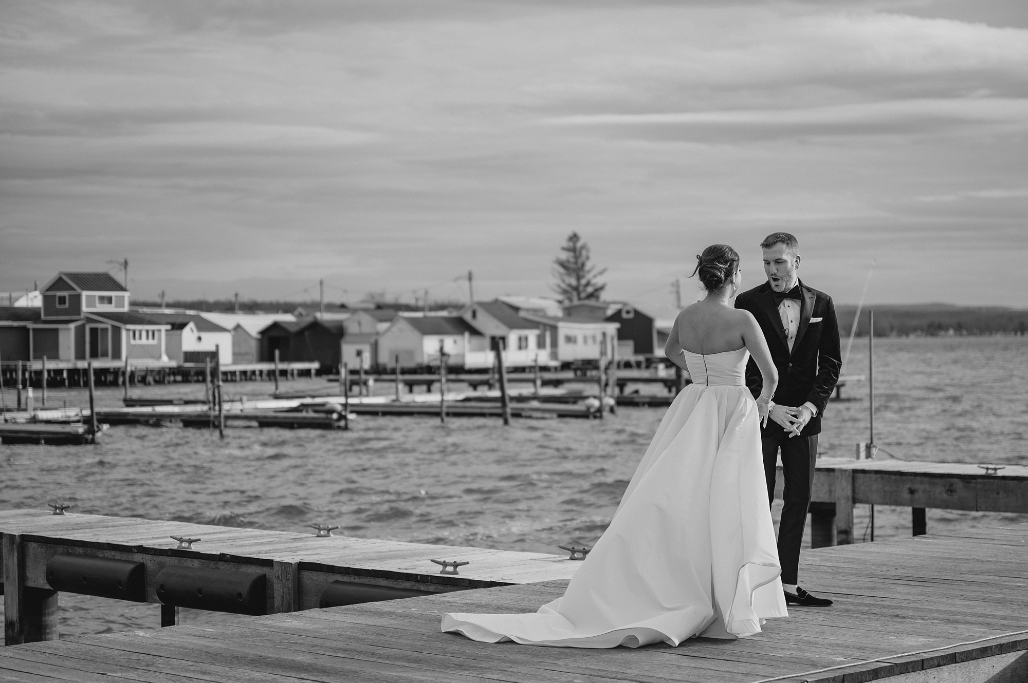 groom turns to look at bride during first look on wooden dock at the Lake House at Canandaigua